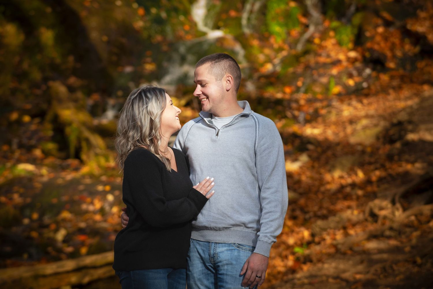 Couple sharing a romantic moment among vibrant autumn foliage in a forest setting.