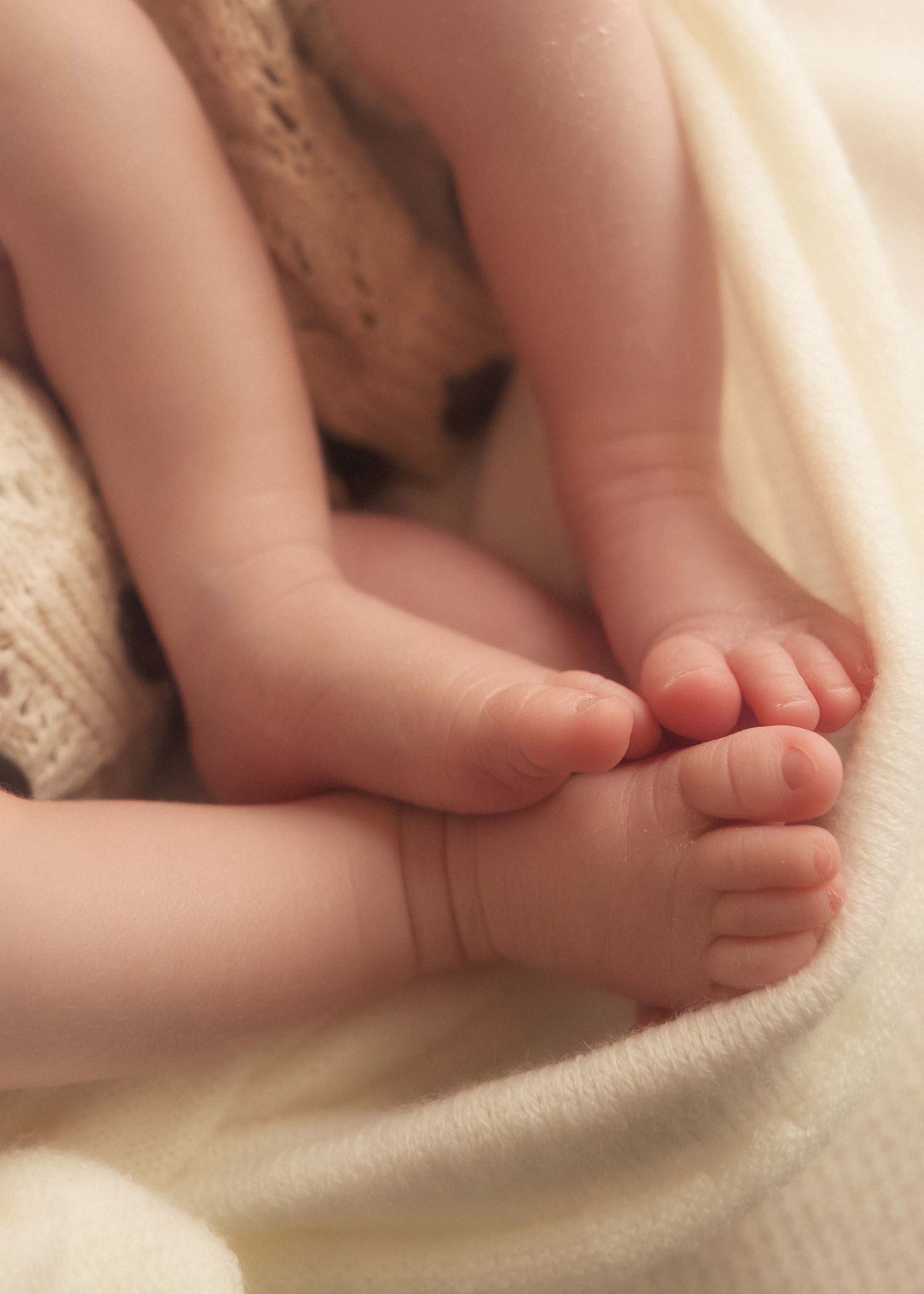Close-up of tiny newborn baby feet resting on a soft cream knit blanket, perfect for nursery decor inspiration.