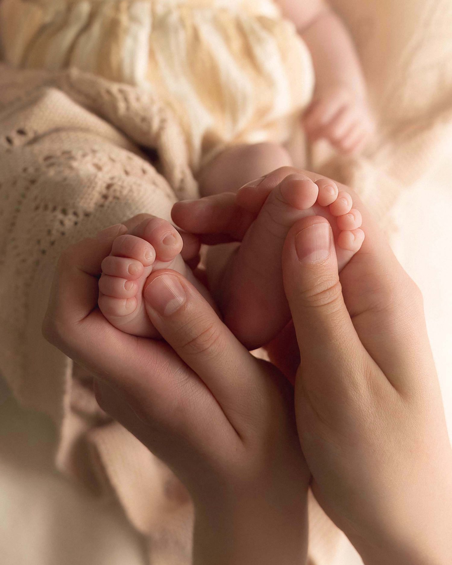 Adult hands gently cradling tiny newborn baby feet, showcasing a tender moment of parental love and connection.