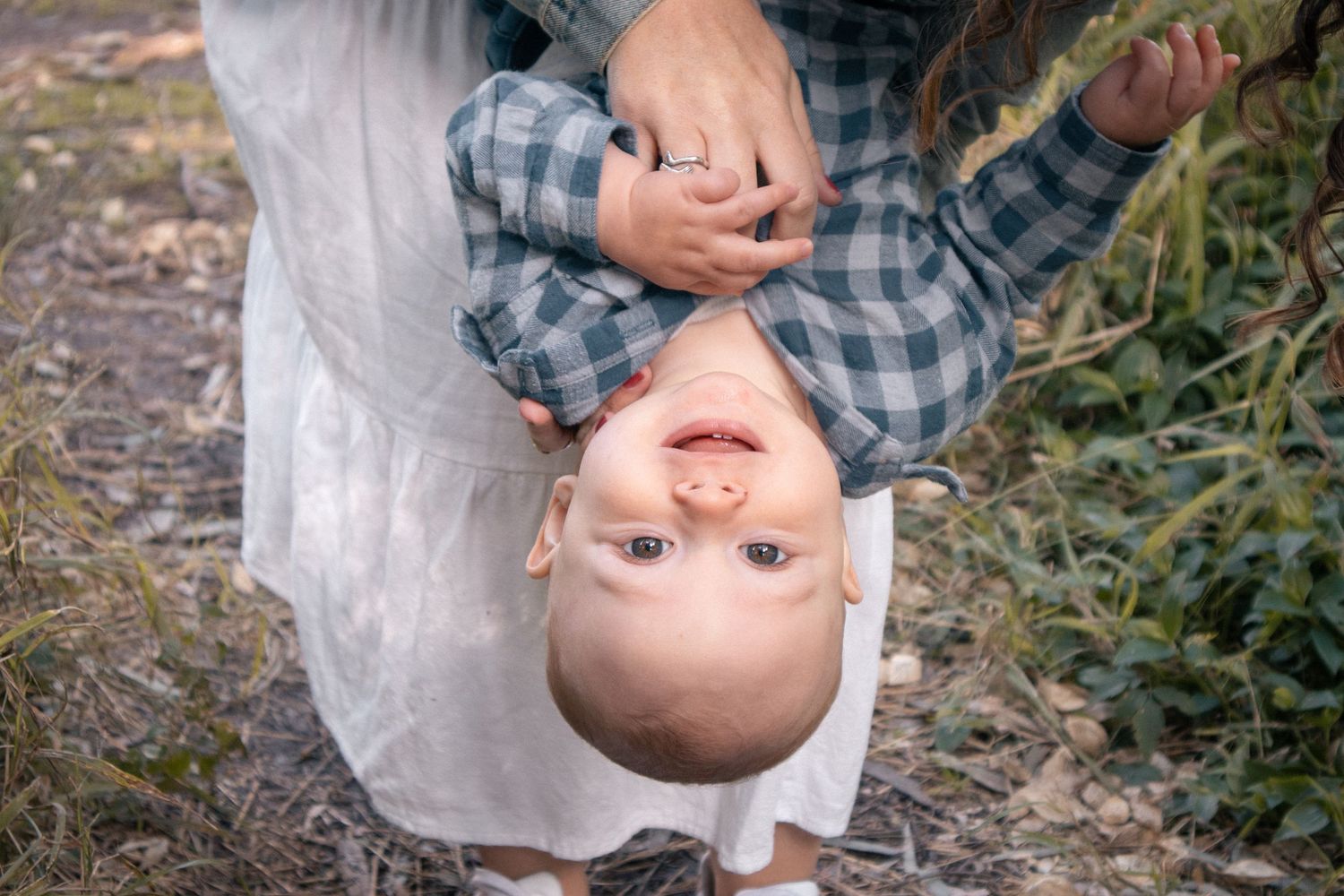 Playful outdoor family moment of parent holding child upside down