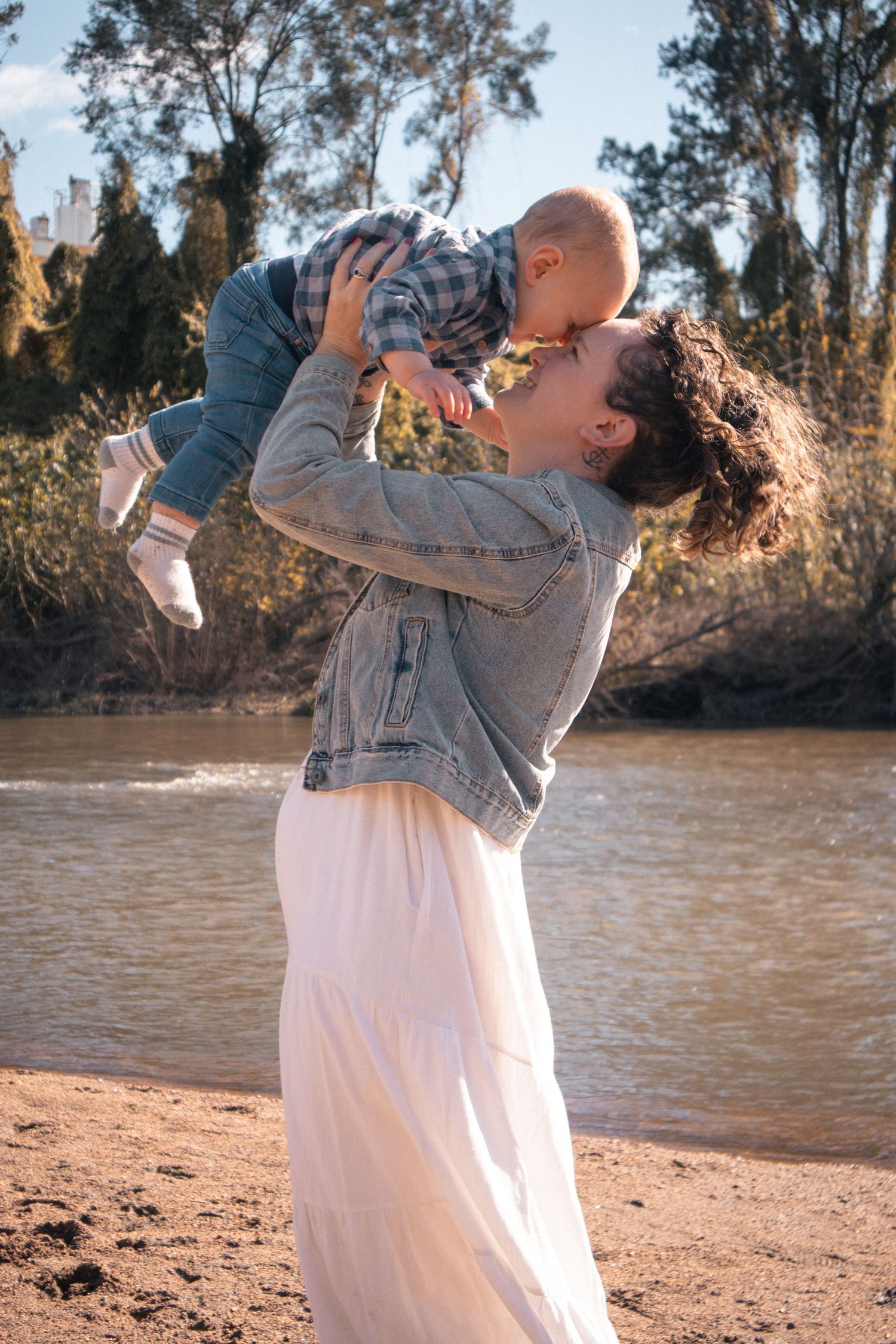 Hunter Valley family photography of mum lifting baby by riverside at golden hour