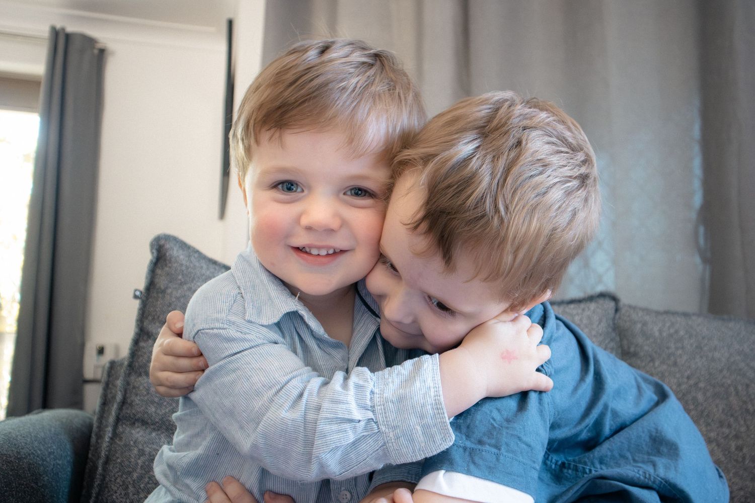 Two young siblings hugging on couch during relaxed in-home family session