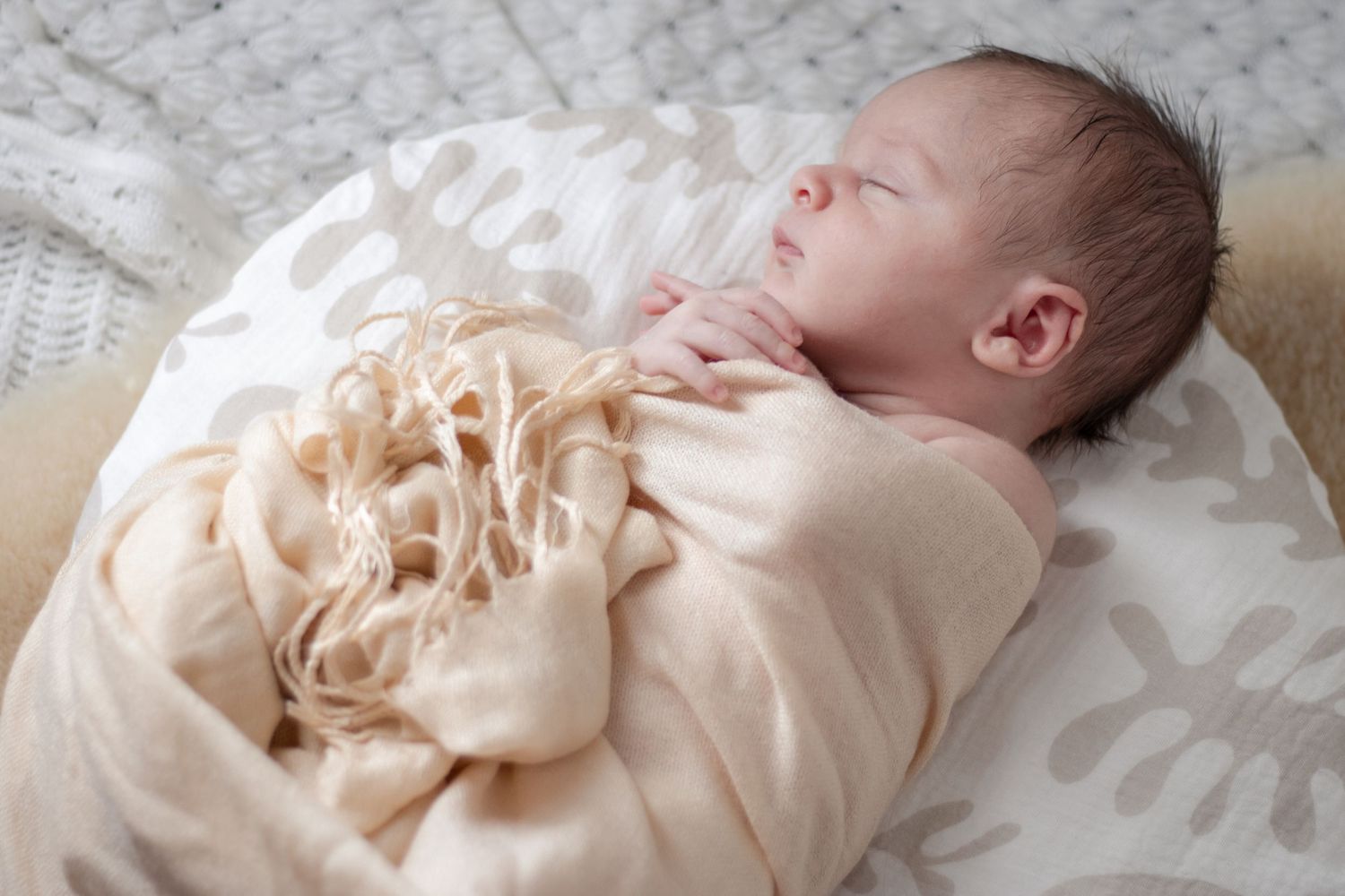 Lifestyle newborn photo of sleeping baby wrapped in neutral tones