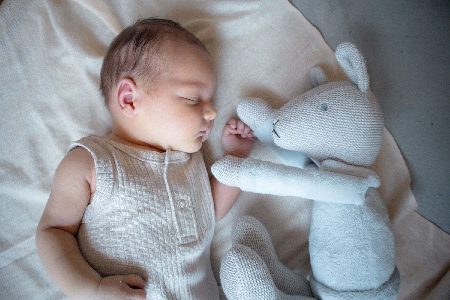 Baby lying with soft toy during relaxed in-home newborn session