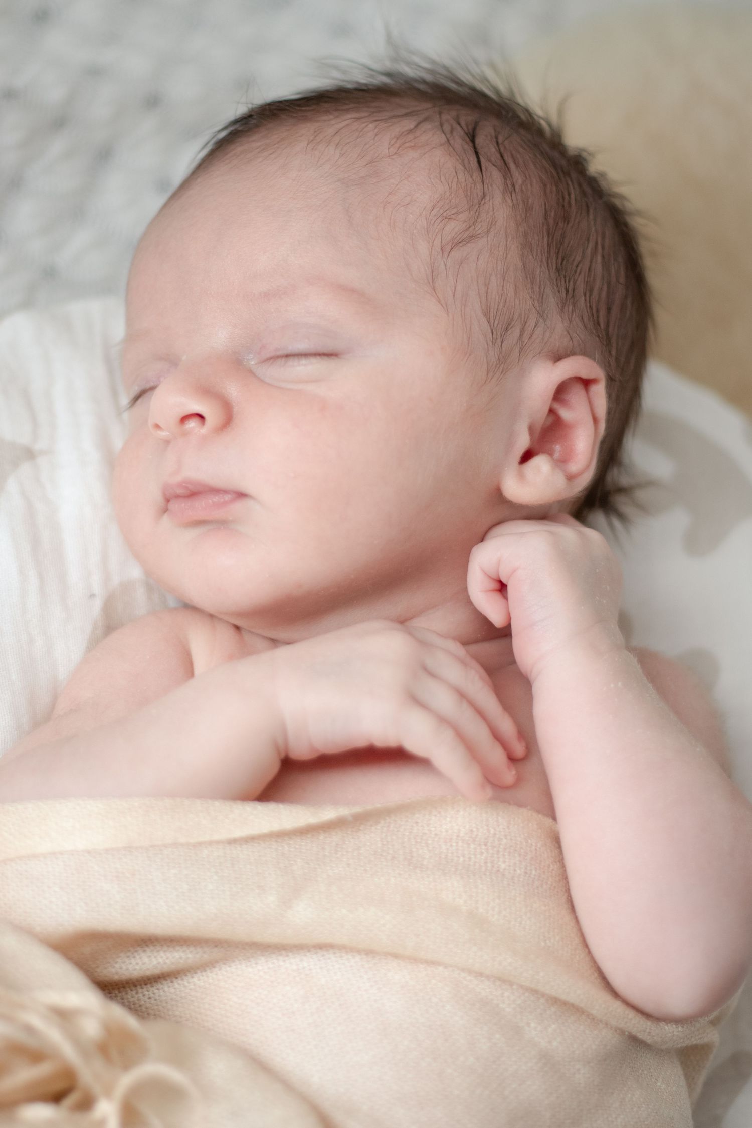 Newborn baby swaddled and resting on bed in softly lit bedroom