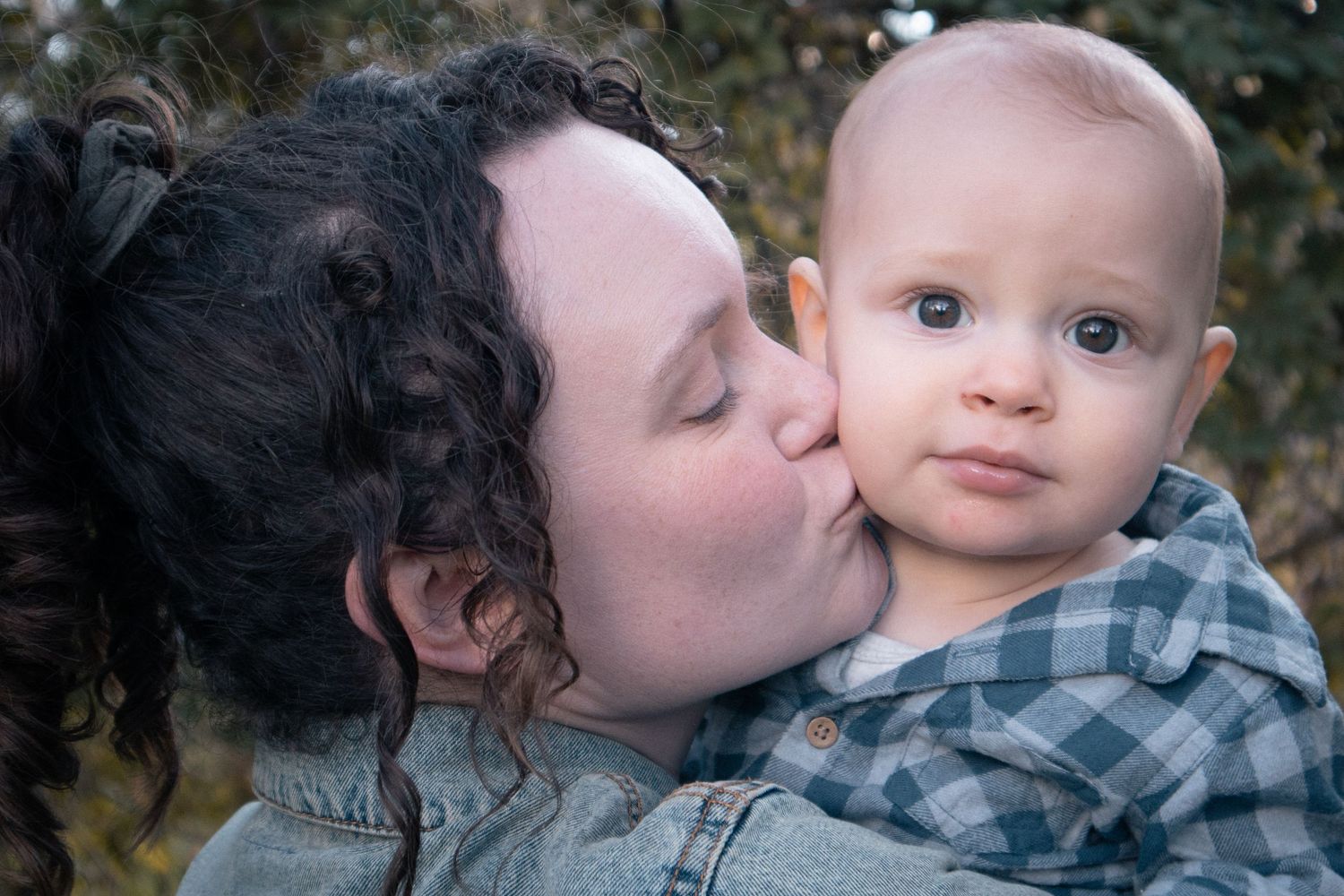 Close-up of mother kissing baby on cheek during outdoor lifestyle session