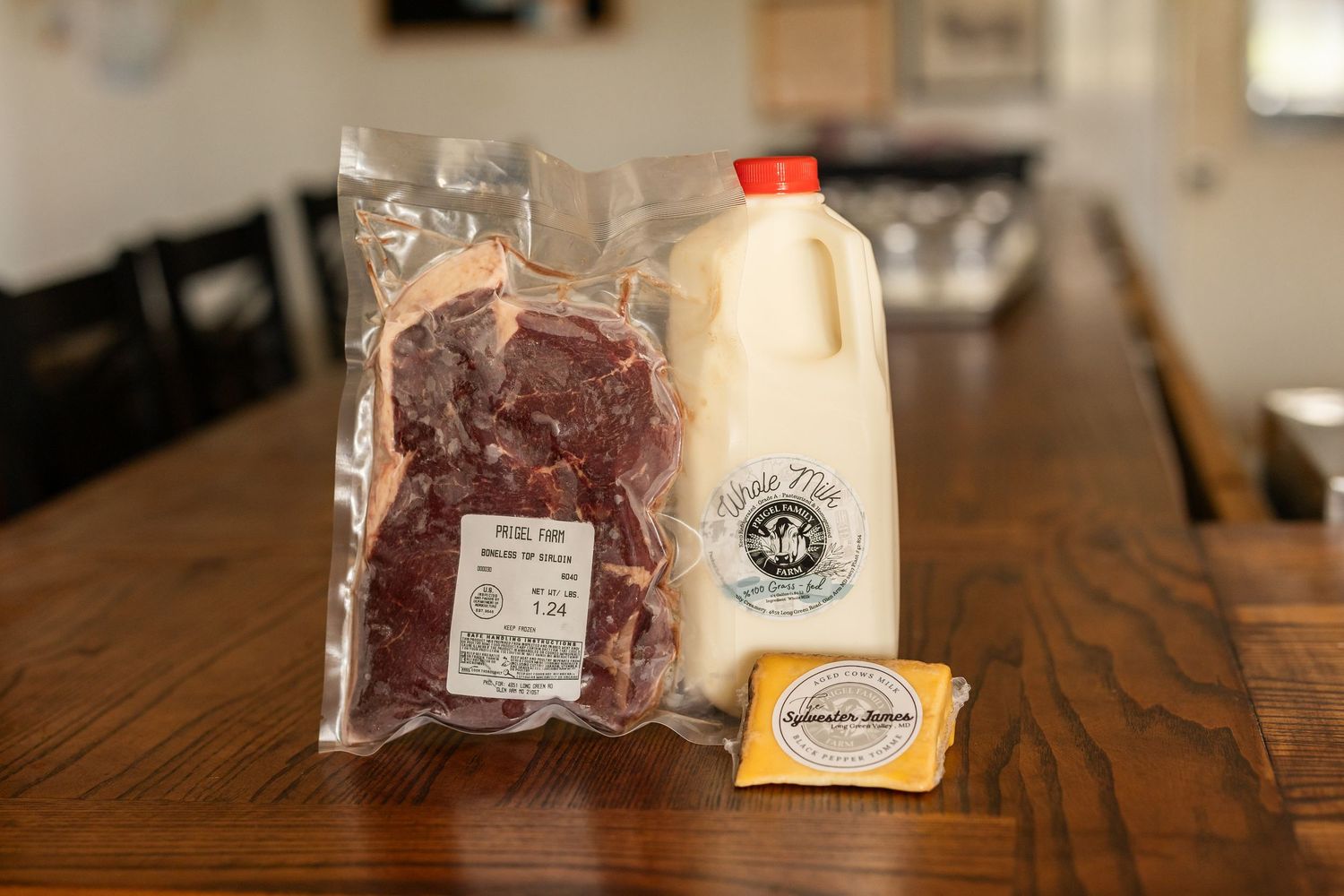 Vacuum-sealed beef steak, half-gallon of farm-fresh milk, and a block of butter displayed on a wooden table.