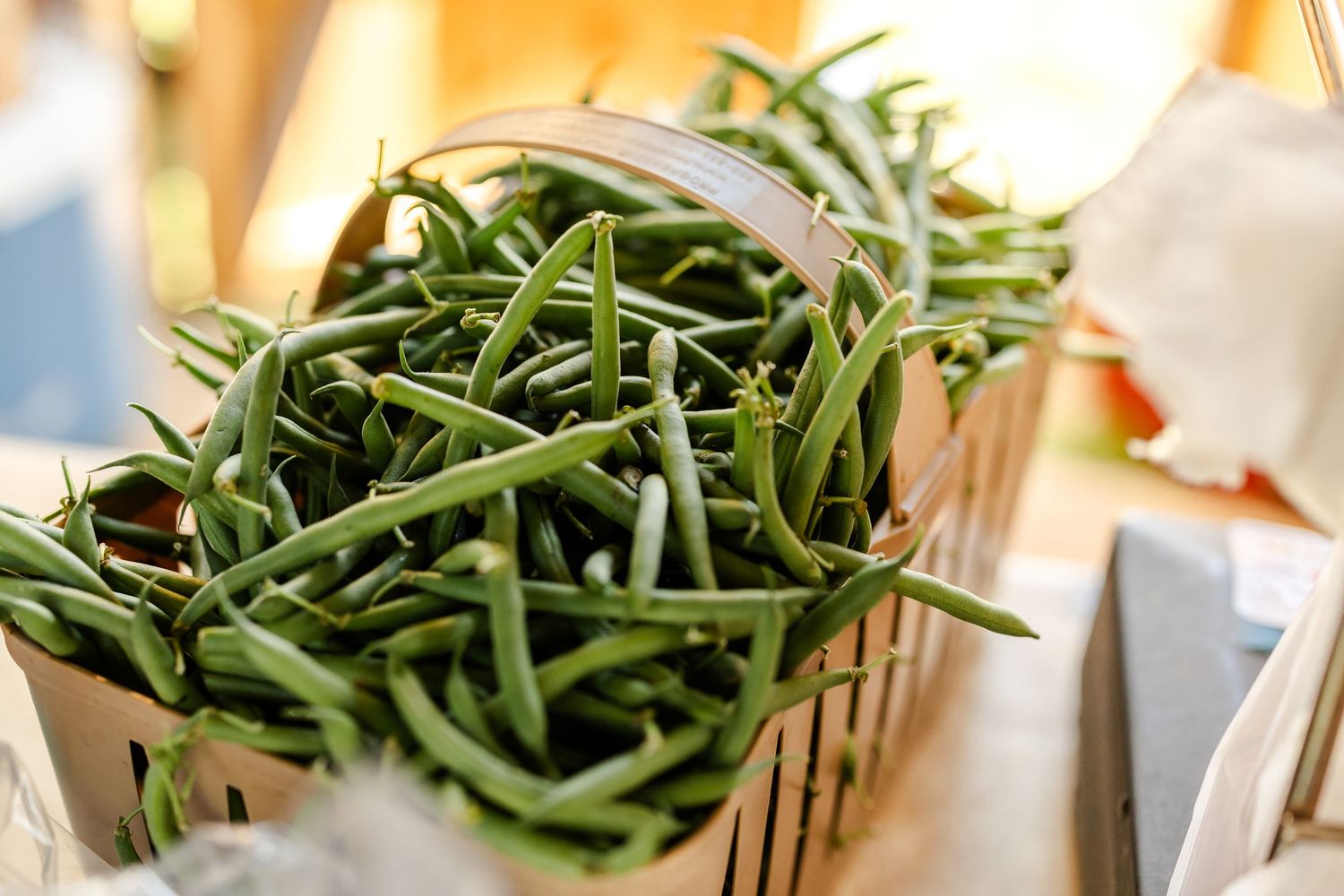 Fresh green beans piled high in a wooden basket.