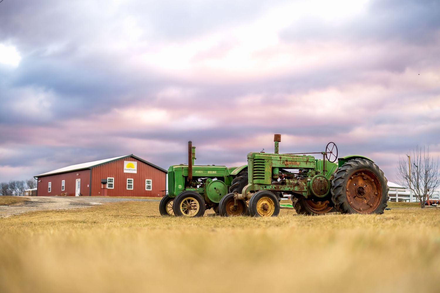 Vintage tractors and farm equipment lined up against a rural sunset landscape on a Maryland farm.