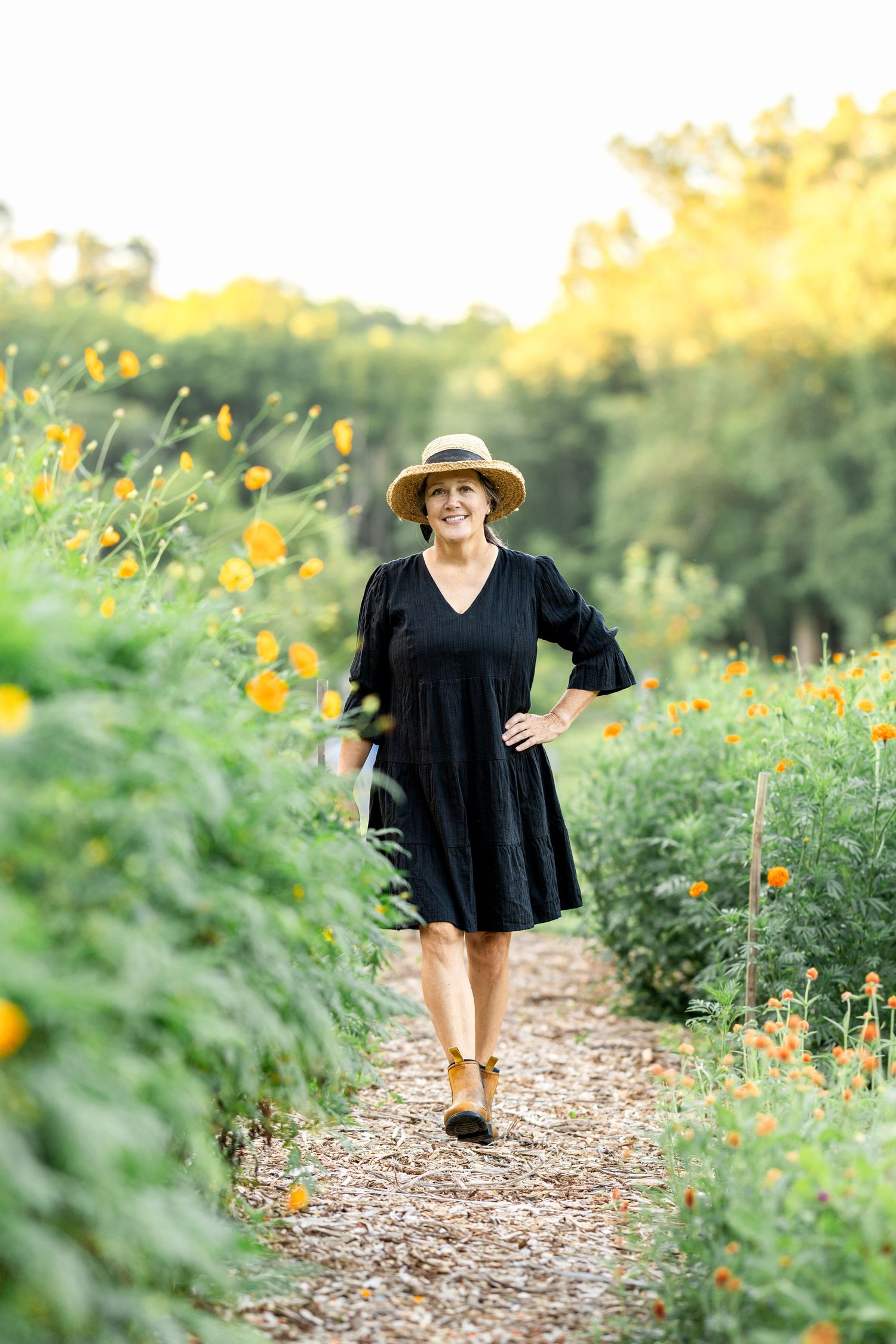 A mulched pathway winds through a garden filled with yellow summer flowers.
