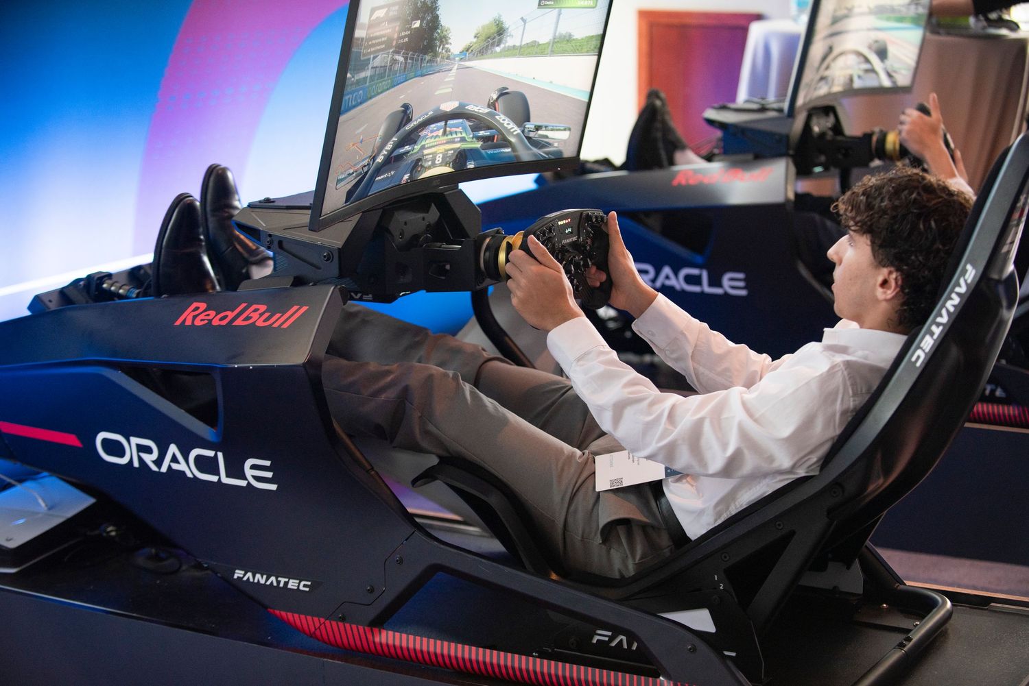 Young man using an Oracle Red Bull Racing F1 simulator with Fanatec steering wheel at a gaming event.