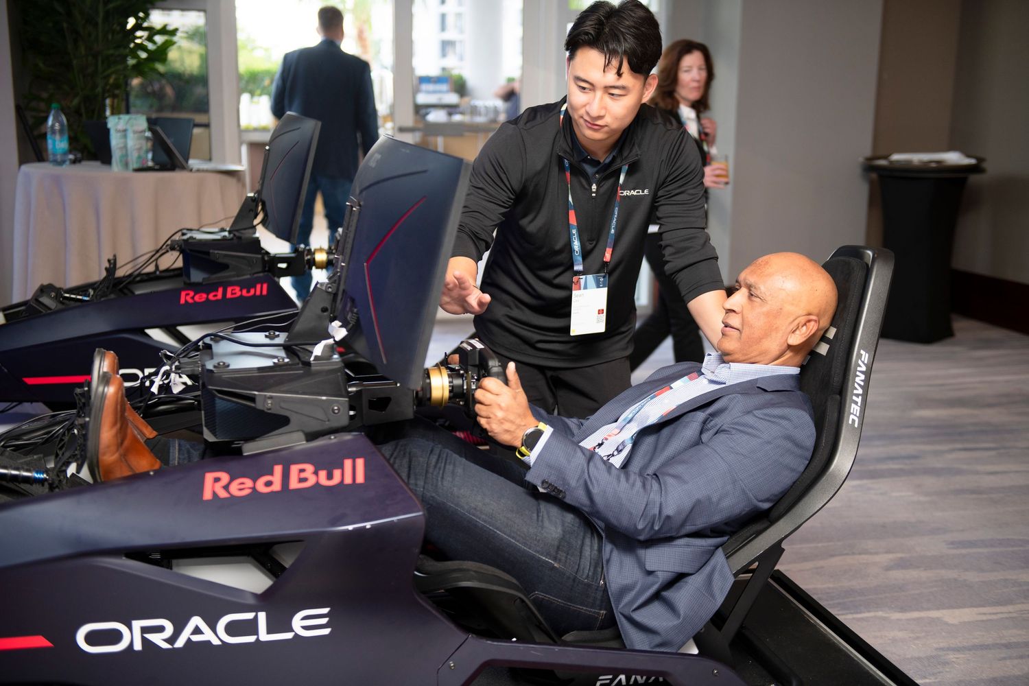 Two men examine an Oracle Red Bull Racing F1 simulator at an indoor corporate event.