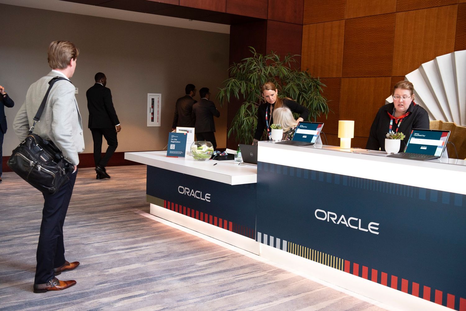 Attendees check in at the Oracle registration desk during a corporate conference event.