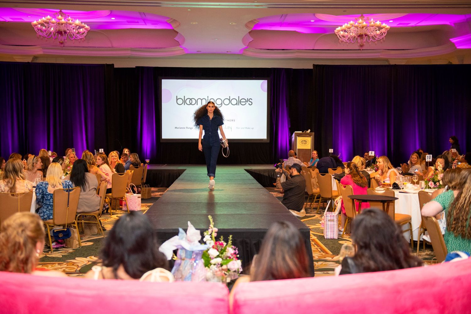 Bloomingdale's fashion show runway event in elegant ballroom with model walking catwalk before seated audience.