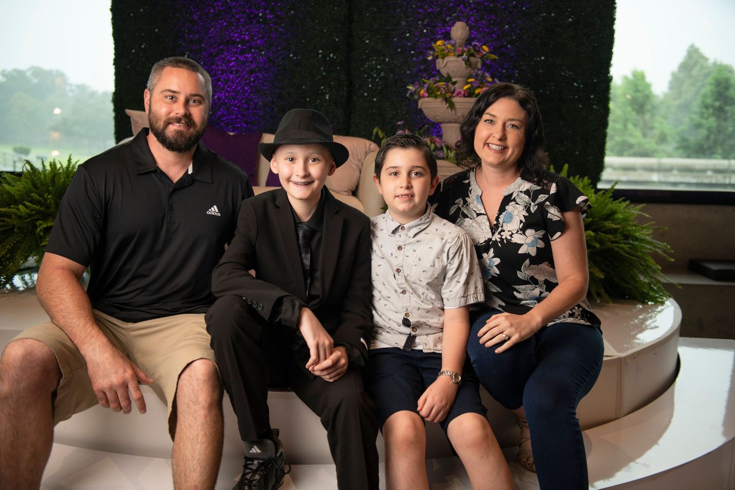 Family of four posing together indoors at a formal event, with two adults and two children smiling for a portrait.