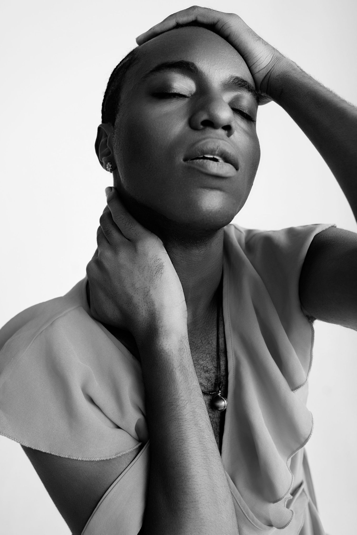 Black and white portrait of a person with closed eyes holding their neck and head in a serene pose.