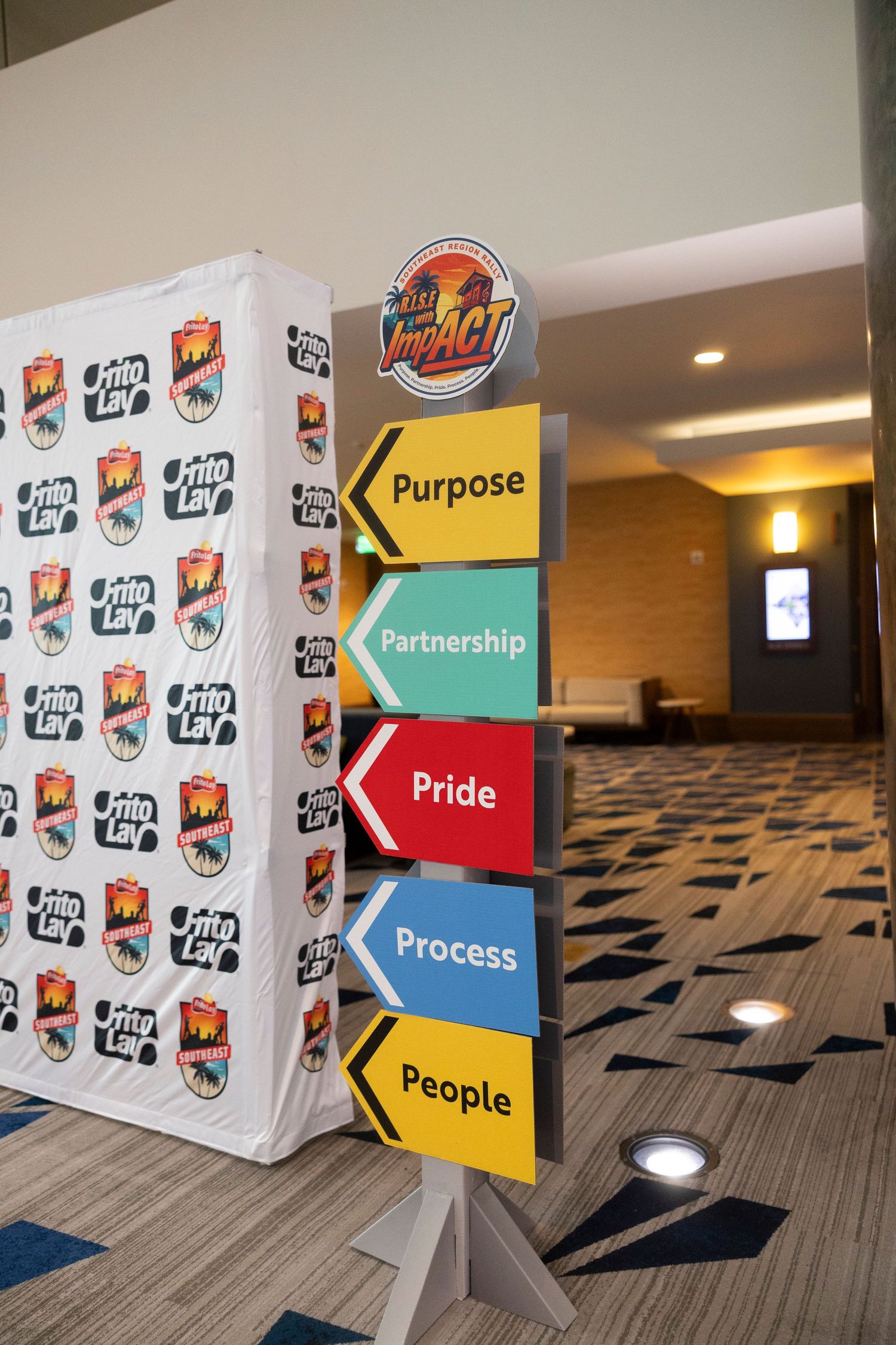 Frito-Lay IMPACT event display with colorful arrow signs showing Purpose, Partnership, Pride, Process, and People values.