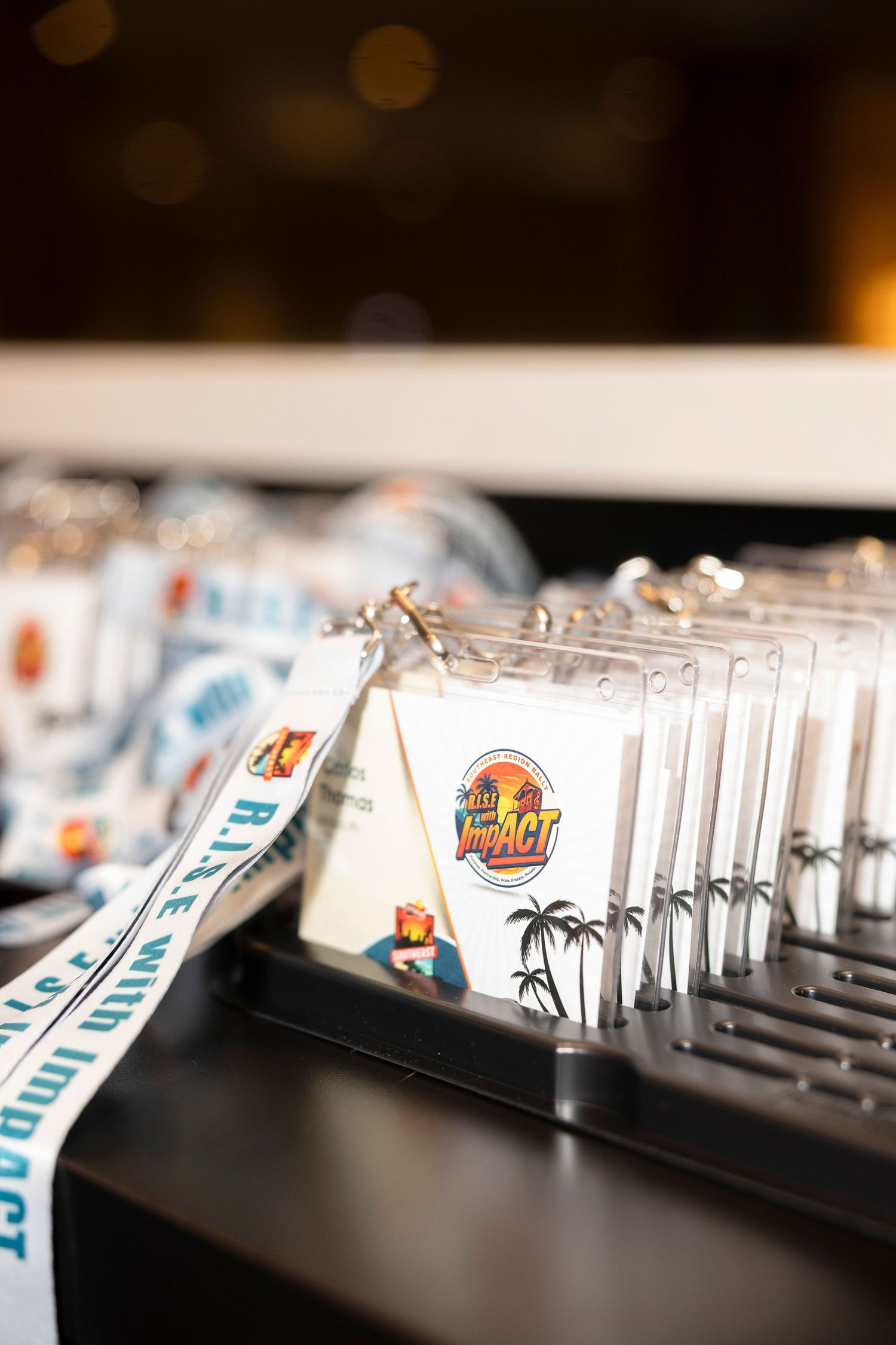 Conference lanyards and badge holders displaying the Rise with Impact logo arranged on a display table.