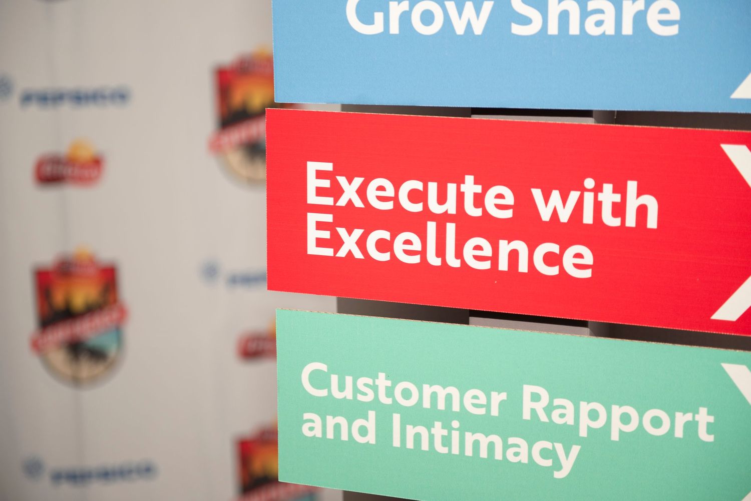 Corporate signage displaying business strategy pillars: Grow Share, Execute with Excellence, and Customer Rapport and Intimacy.