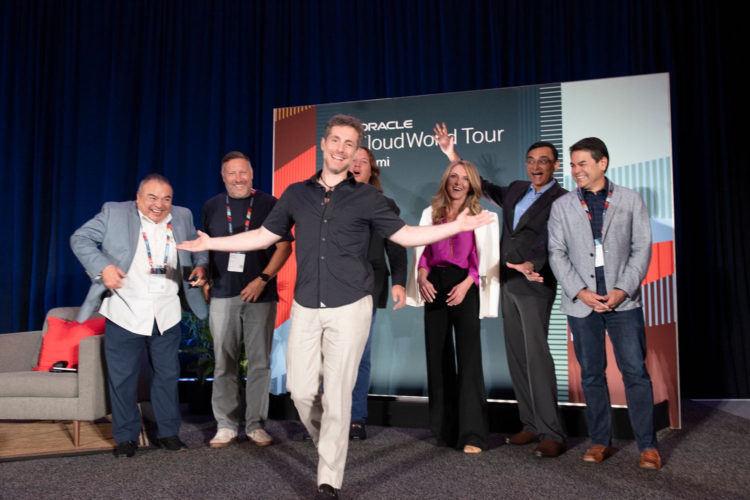 Group of professionals celebrating on stage at Oracle Cloud World Tour event, smiling and posing energetically.