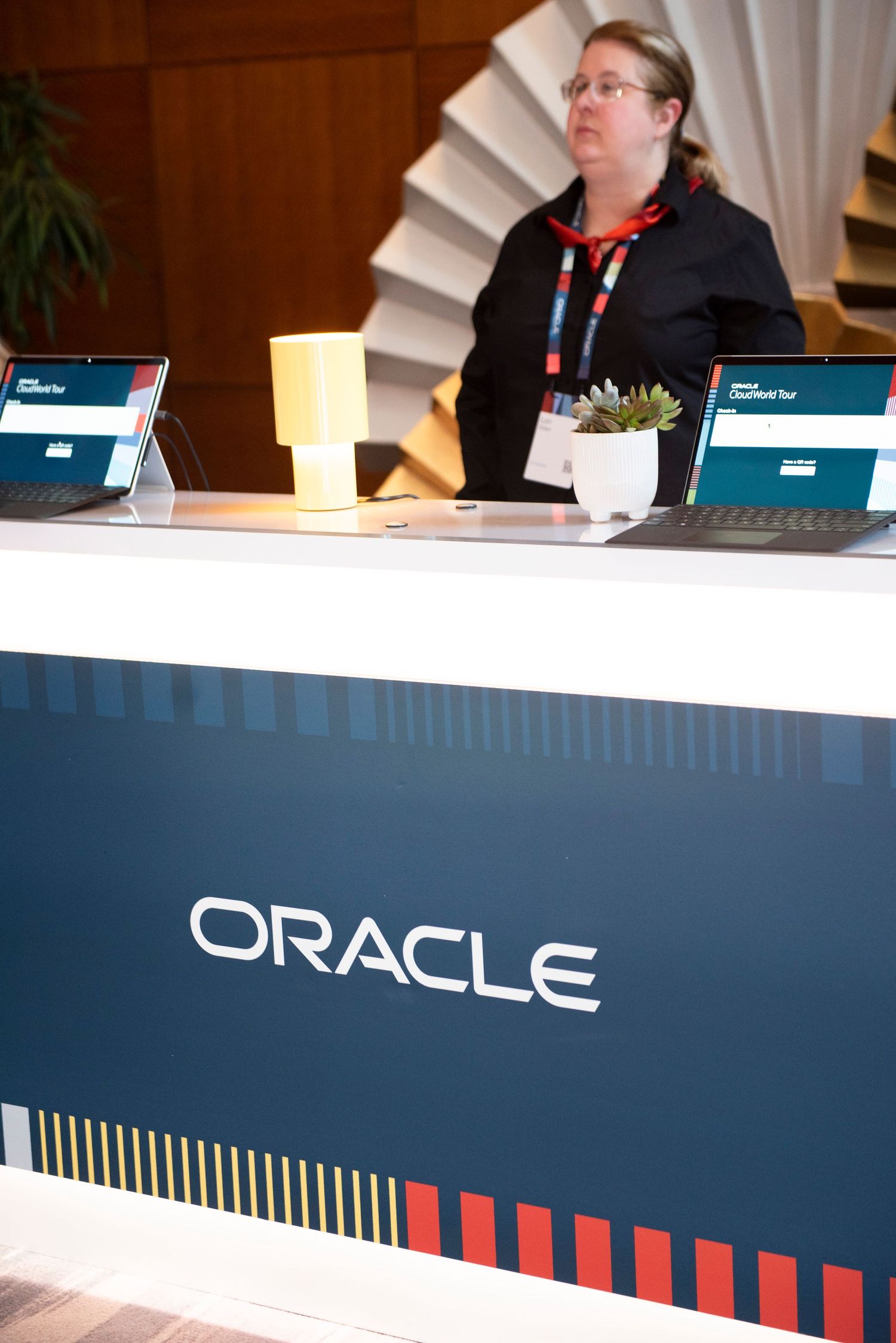 Woman at an Oracle branded reception desk with laptops at a corporate conference event.