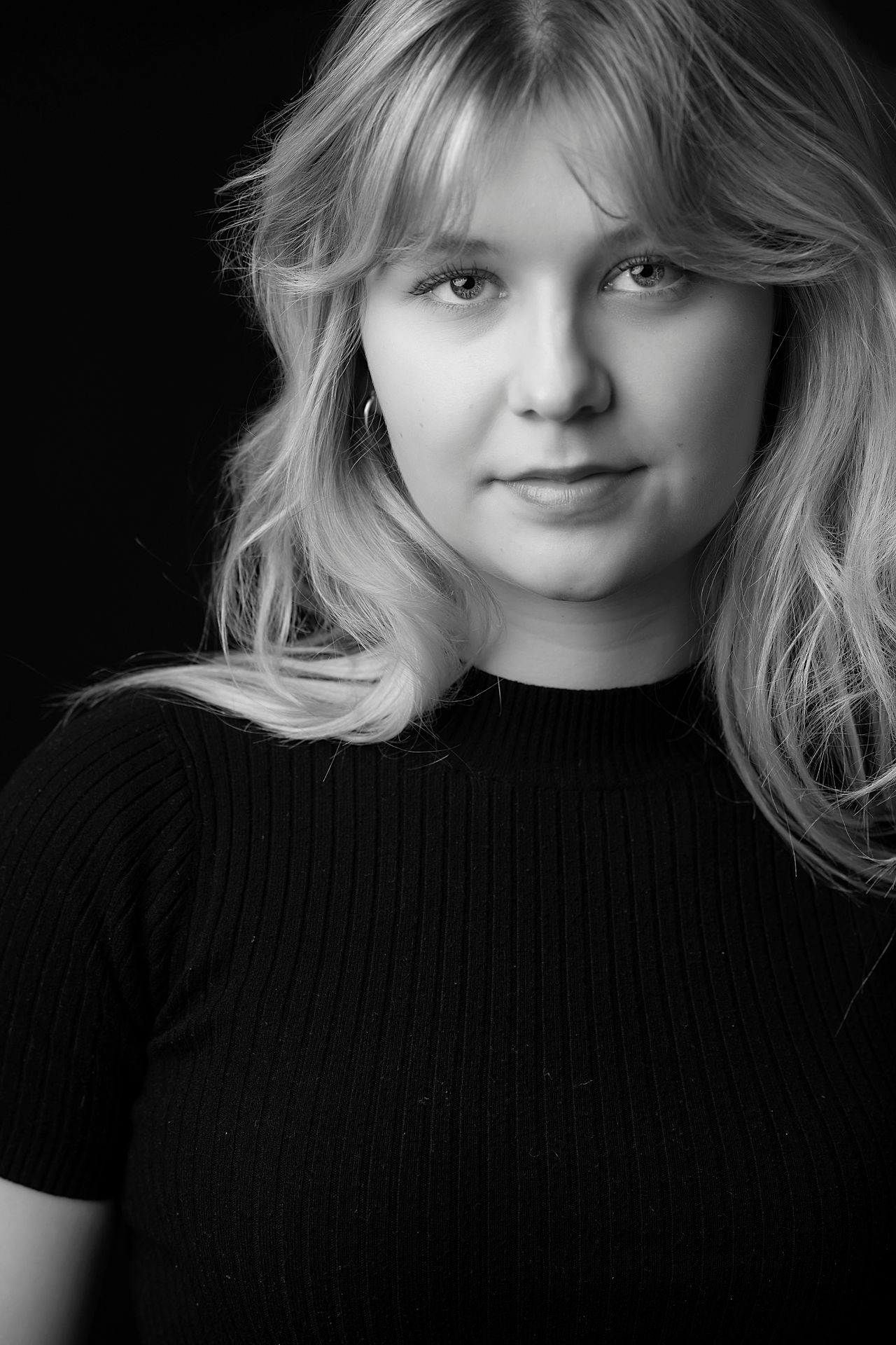 Black and white portrait of a young blonde woman wearing a black turtleneck top.