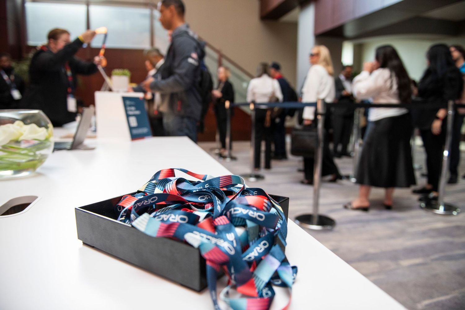 A tray of colorful lanyards on a registration table at a busy professional conference event.