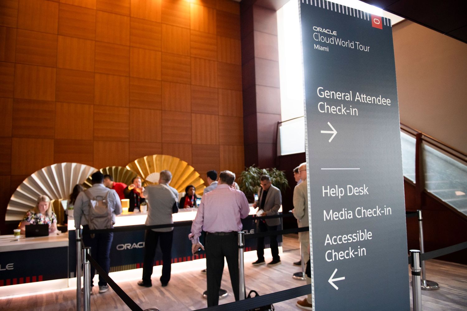 Oracle CloudWorld Tour Miami event check-in area with directional signs for general attendees, help desk, and media.