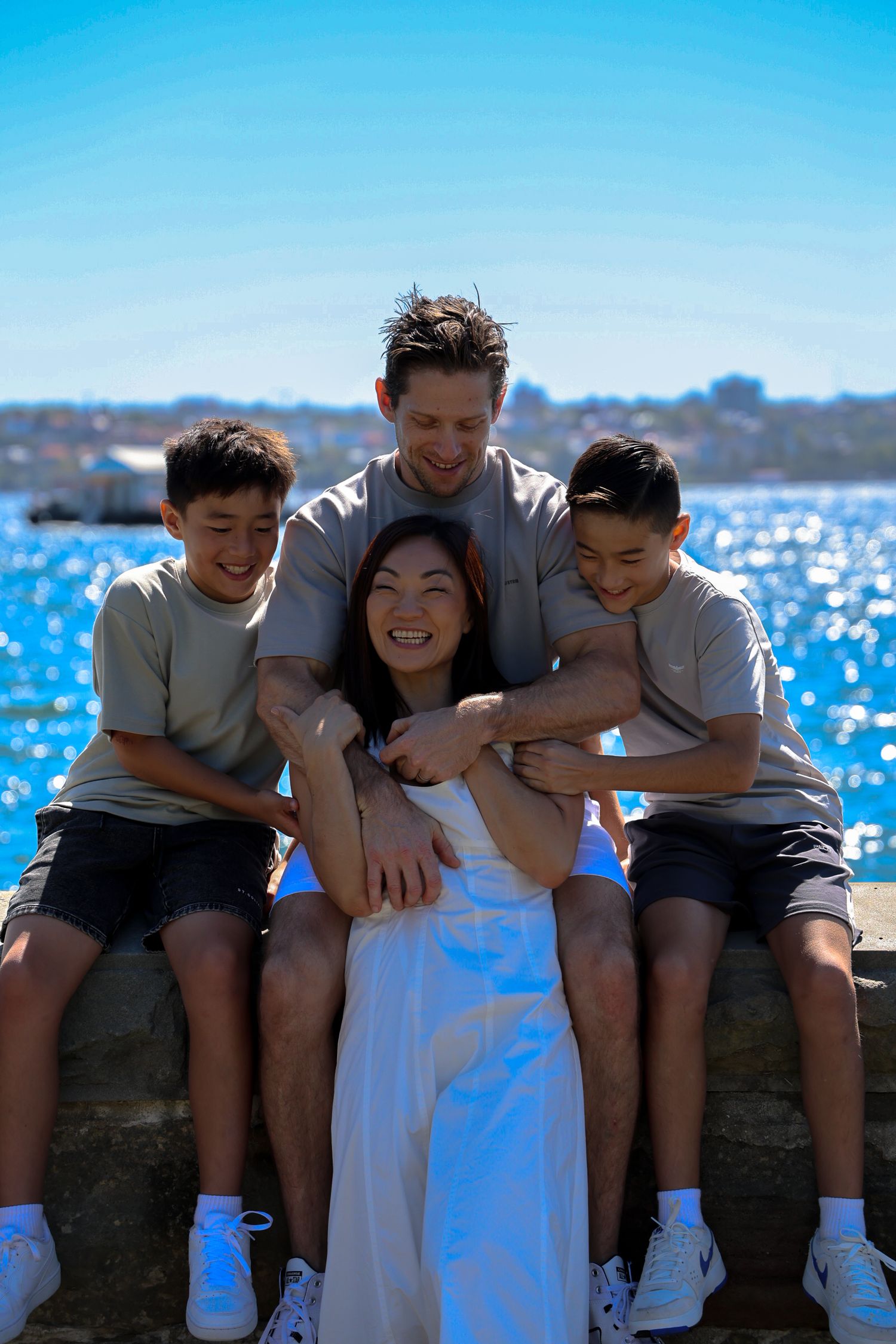 A family with mum laughing while her two sons tickle her