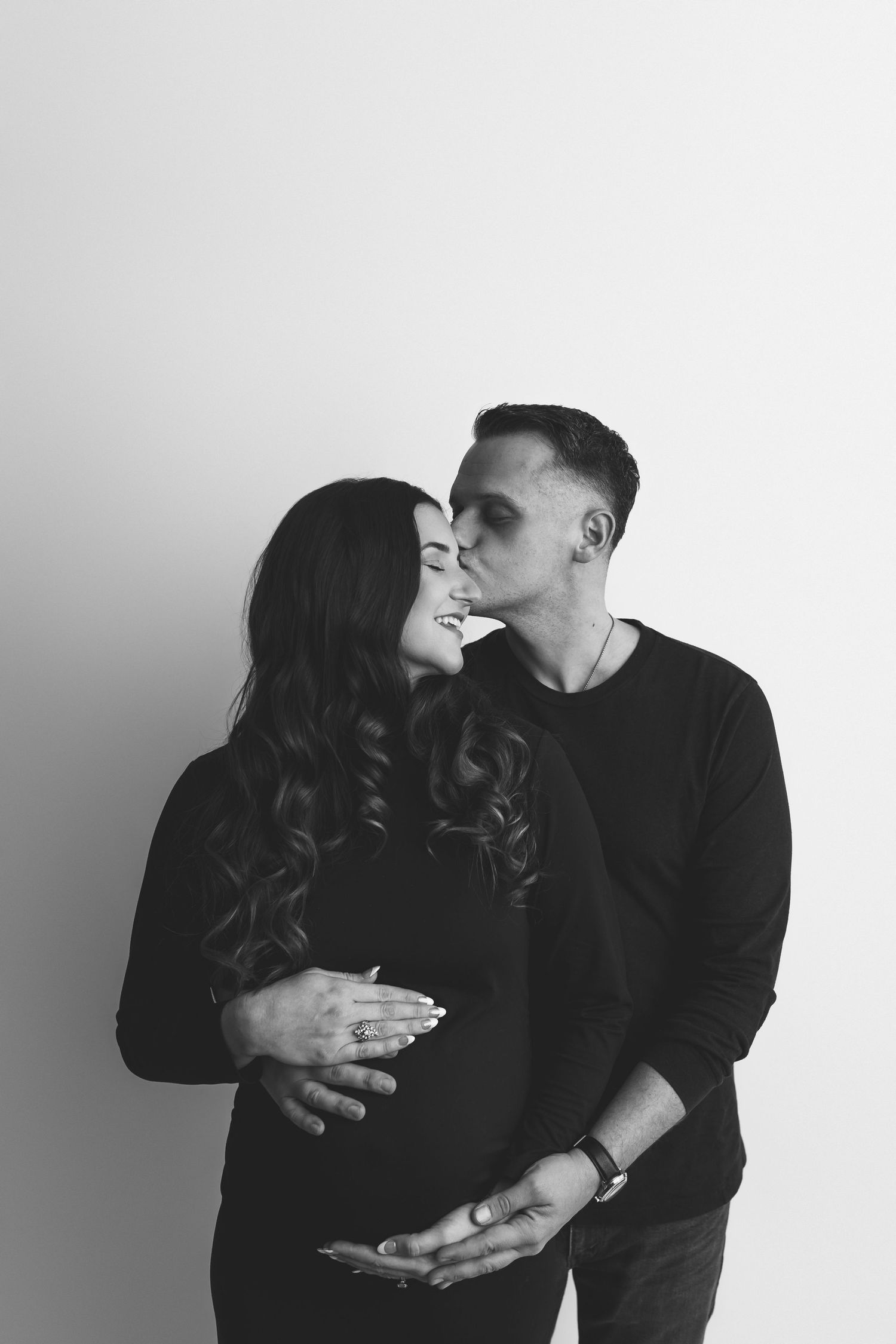 Black and white maternity photo of couple embracing, man kissing pregnant womans cheek tenderly. Maternity Photography Texarkana TX