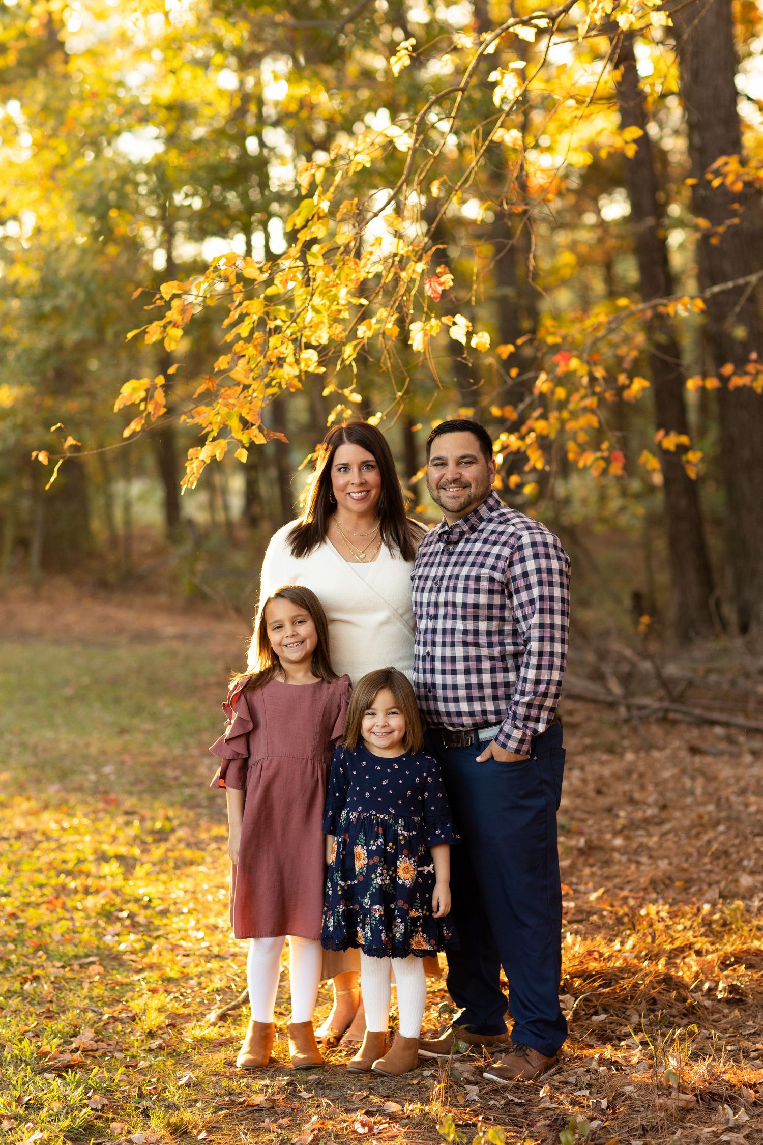 Family of four posing outdoors among vibrant autumn foliage for a fall portrait session. Family Photographer Atlanta Texas