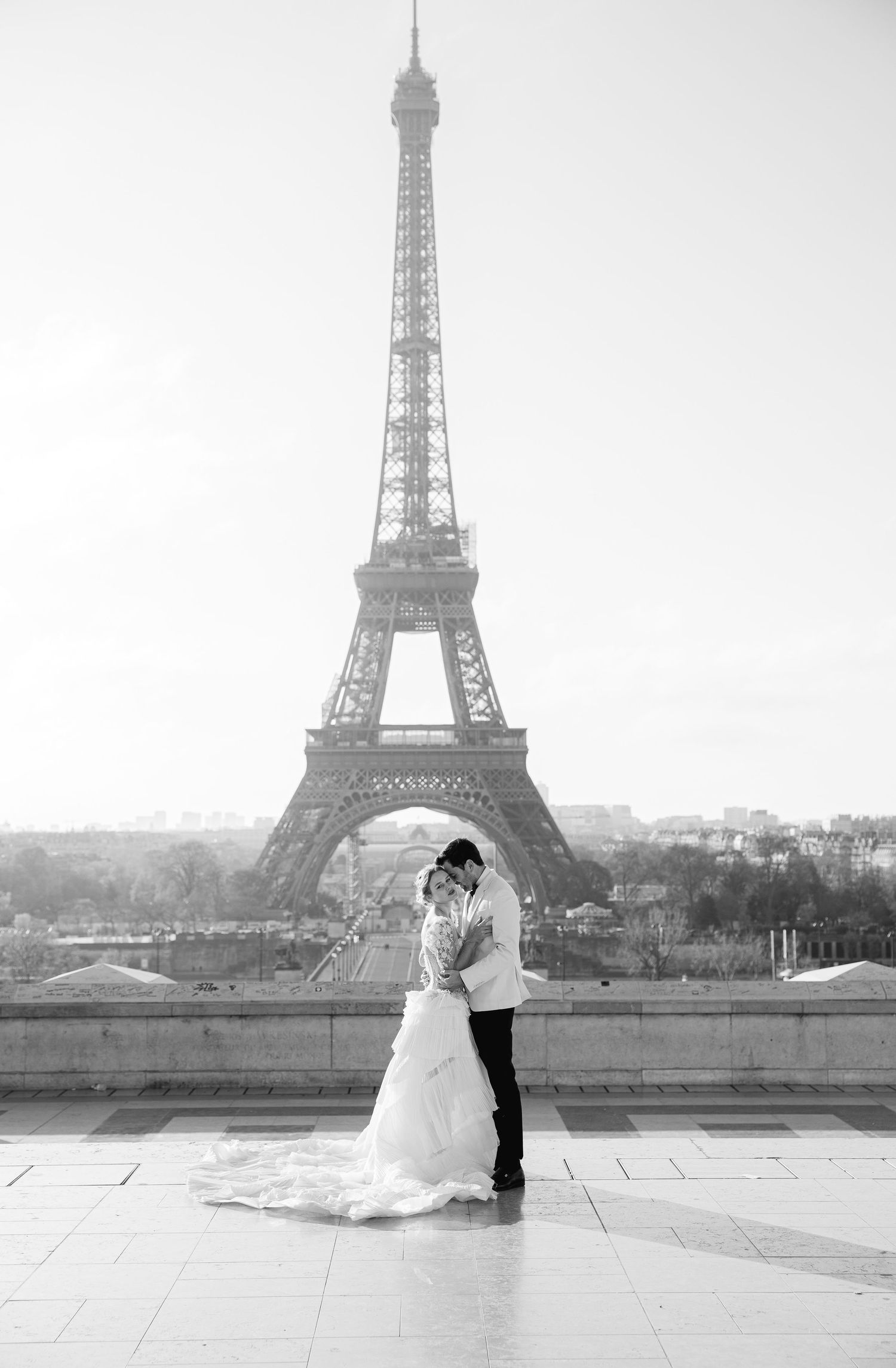 Wedding couple shares intimate moment with Eiffel Tower backdrop in black and white.