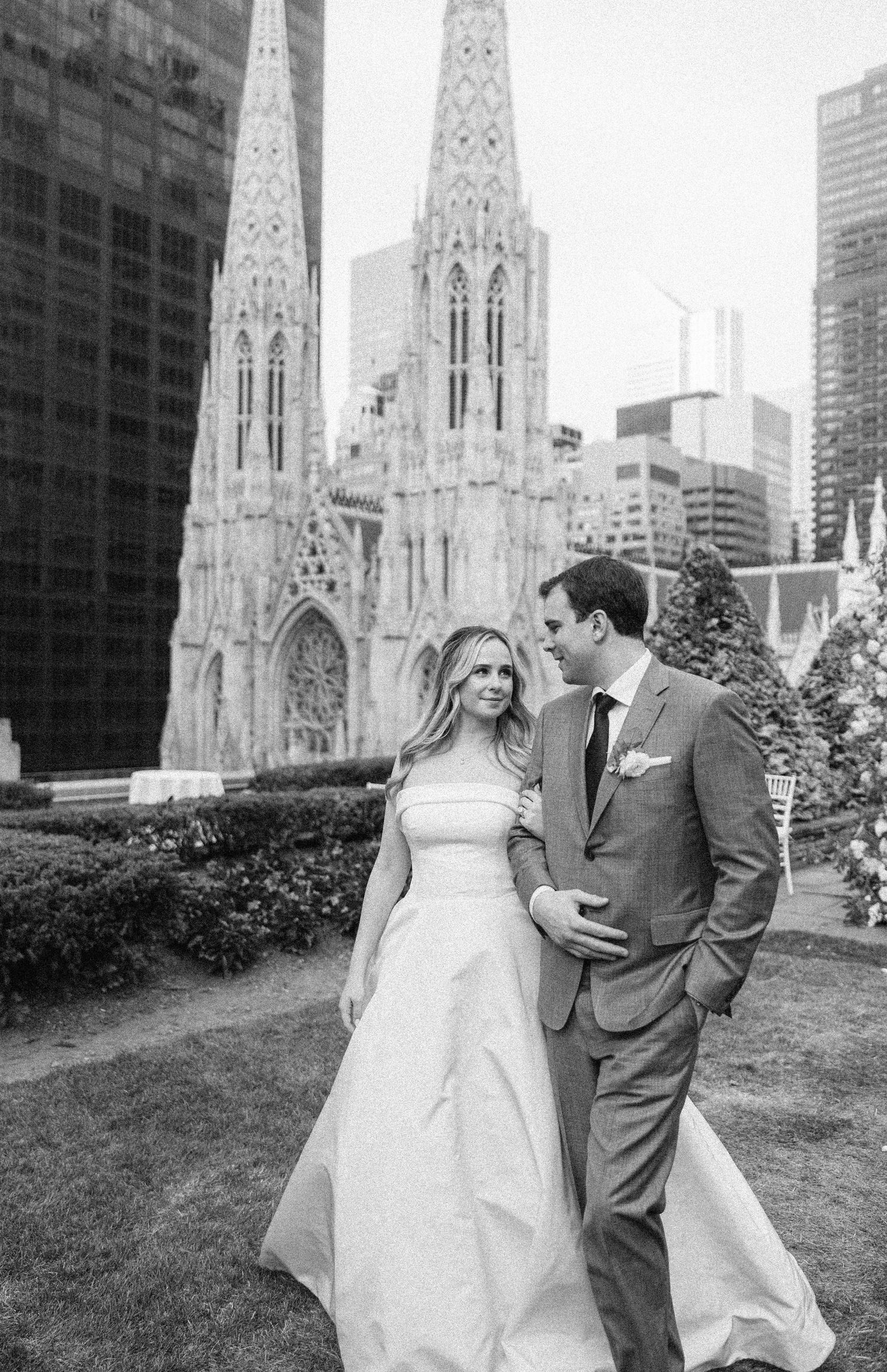 Black and white wedding portrait in front of St. Patrick's Cathedral with NYC skyline.