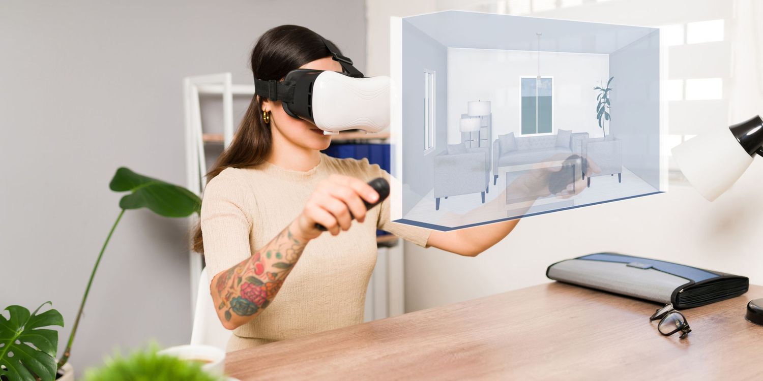 Woman with a tattooed arm wears a virtual reality headset and explores a 3D interior room design on a desk.