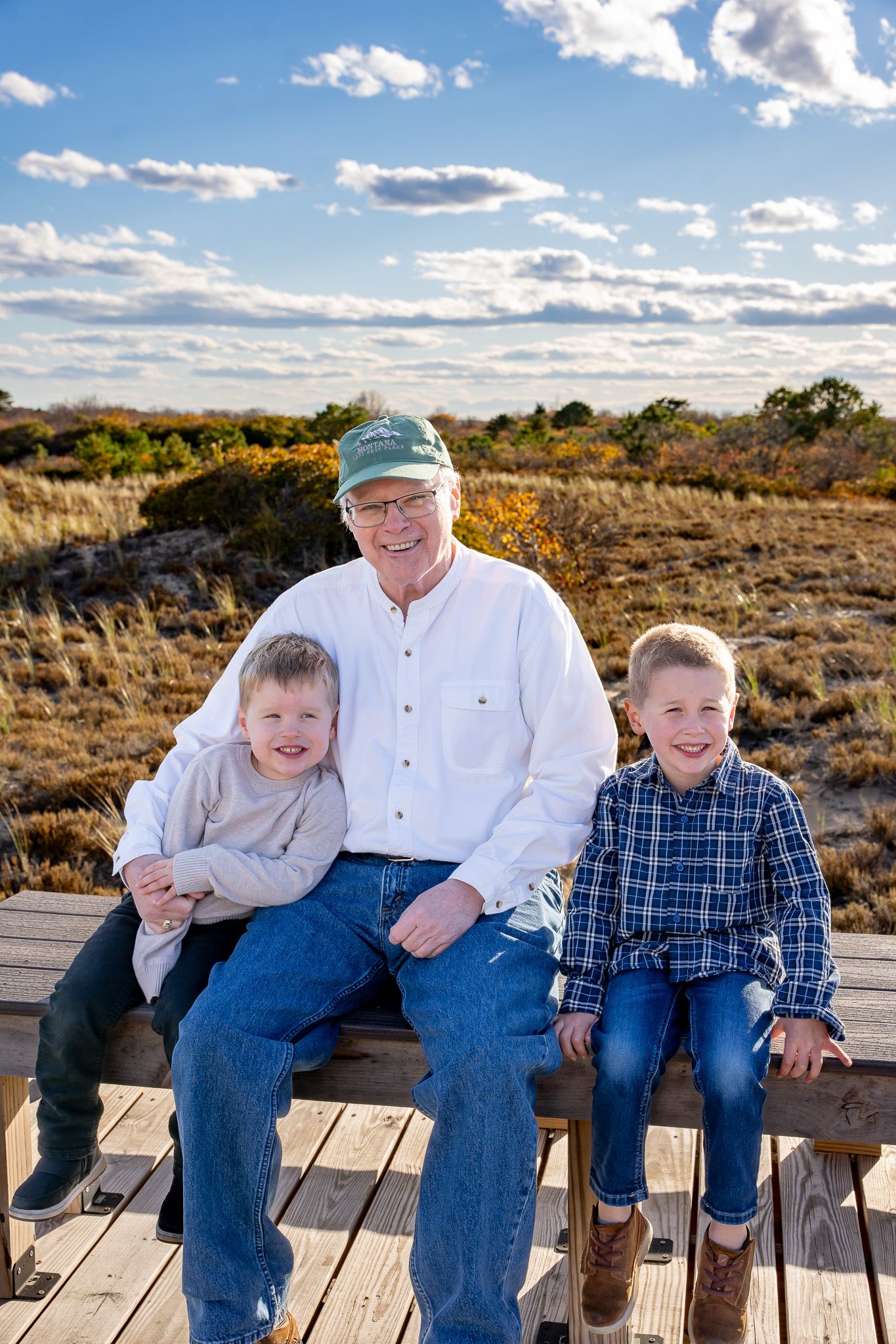 Family portrait of a grandfather sitting on a beach boardwalk with his two young grandsons at Plum Island near Newburyport, Massachusetts