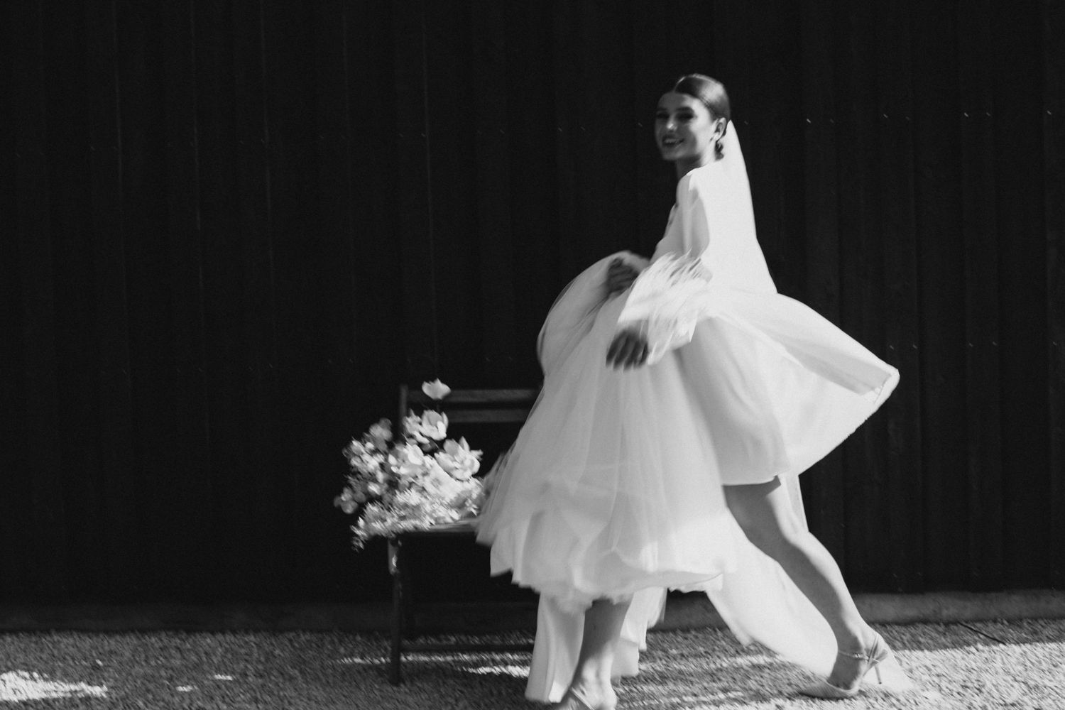 A bride carries her wedding gown after changing into her party dress before late night party at her New England wedding