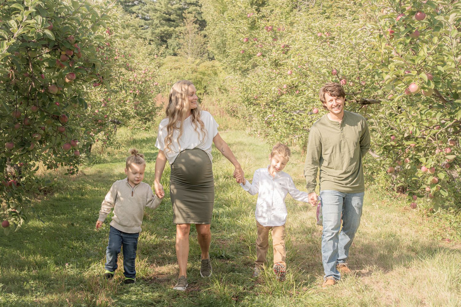Family portrait of a pregnant mom, a dad, and their two sons walking on a Fall day at Applecrest Orchards in Hampton Falls, New Hampshire