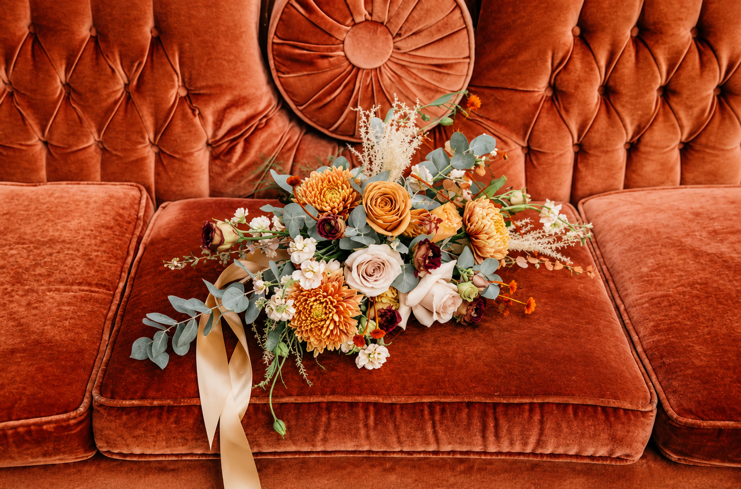 Large bridal floral bouquet with roses, dahlias, and eucalyptus placed on a velvet sofa at a cinematic Newburyport, Massachusetts wedding