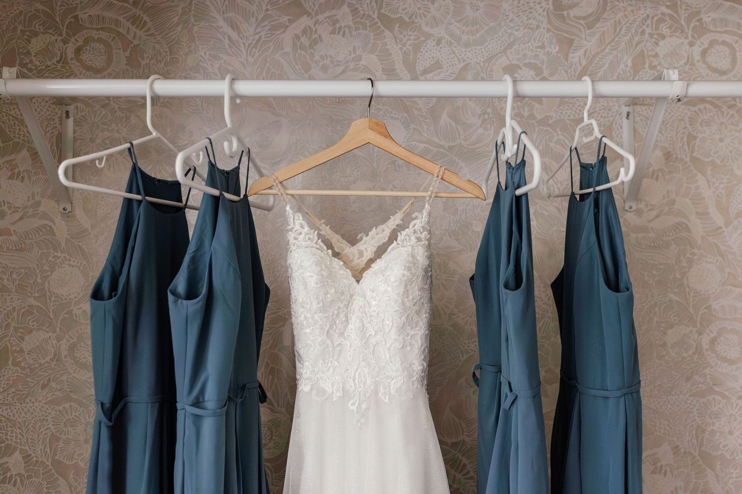 Wedding dress hanging in closet next to bridesmaids dresses before bride gets ready at coastal Maine wedding