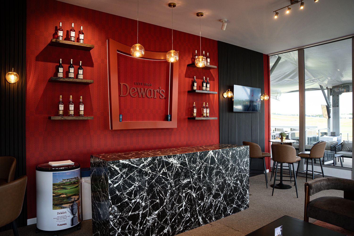 Corporate event photography of a company suite at the U.S. Open Golf Championship in the Hamptons, NY featuring a  moody red Scotch bar