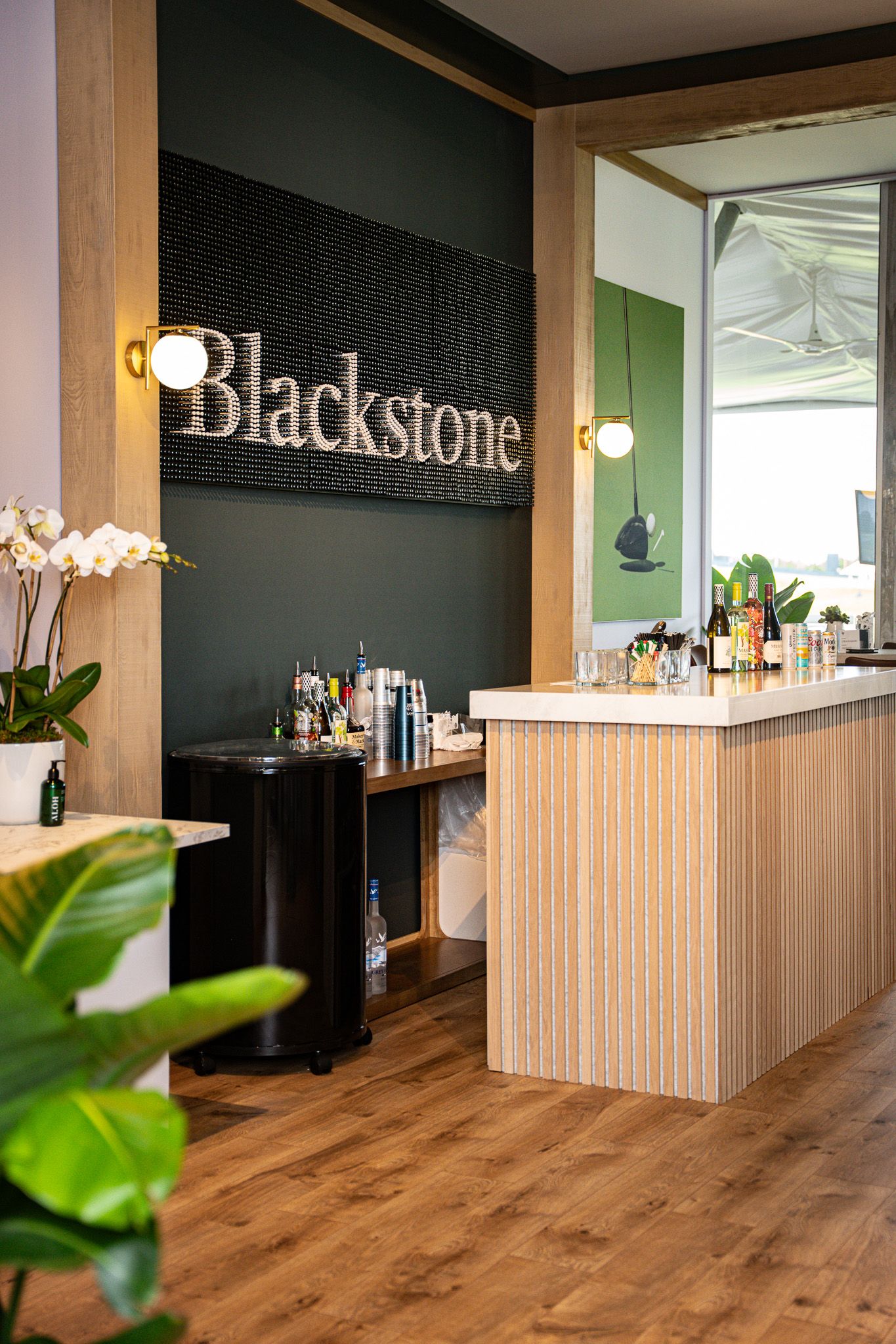 Corporate event photography of a company suite at the U.S. Open Golf Championship in the Hamptons, NY featuring a chic black wall and bar