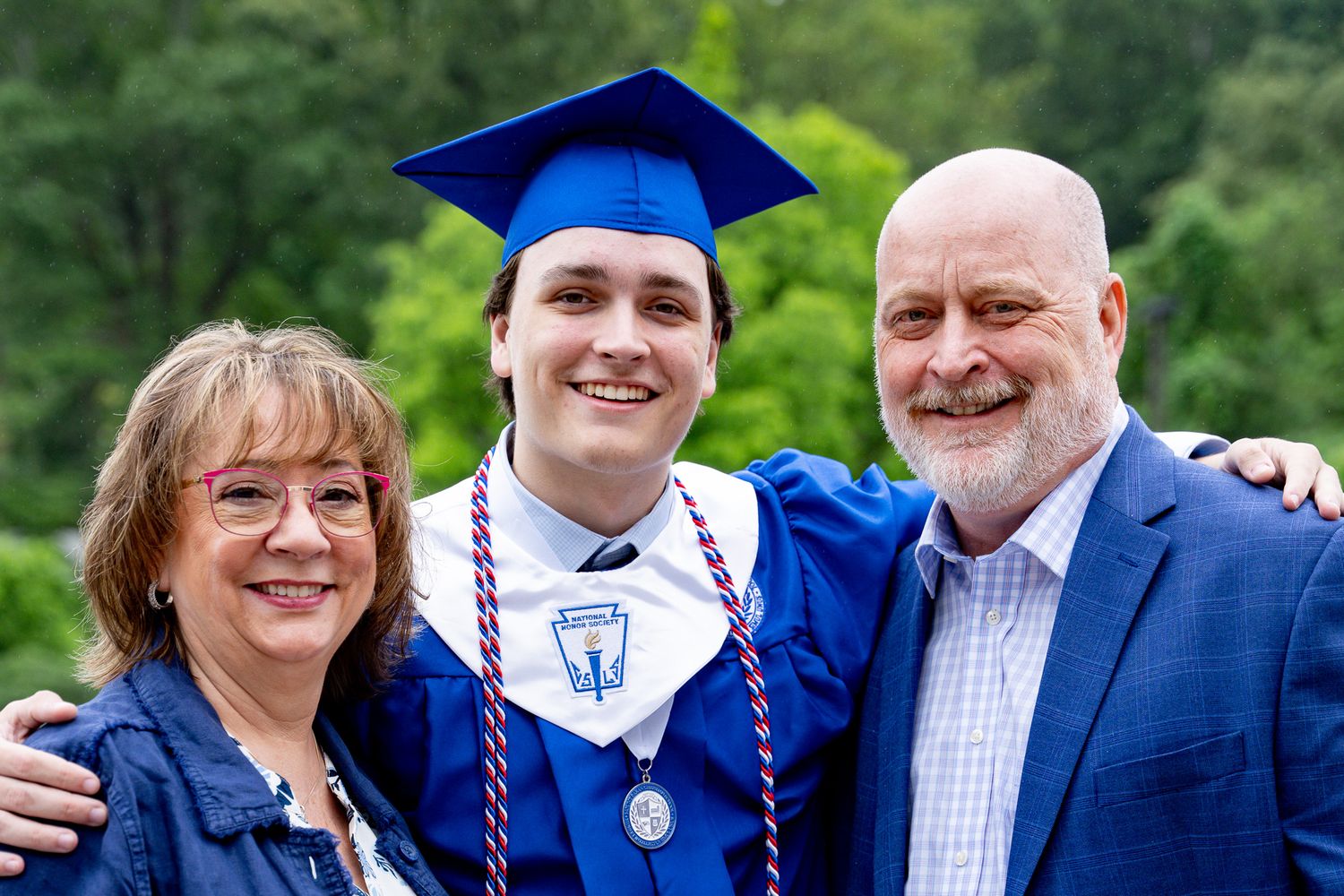 Family portrait of a young man with his arms around his mother and father during his Christian high school graduation party in Georgia