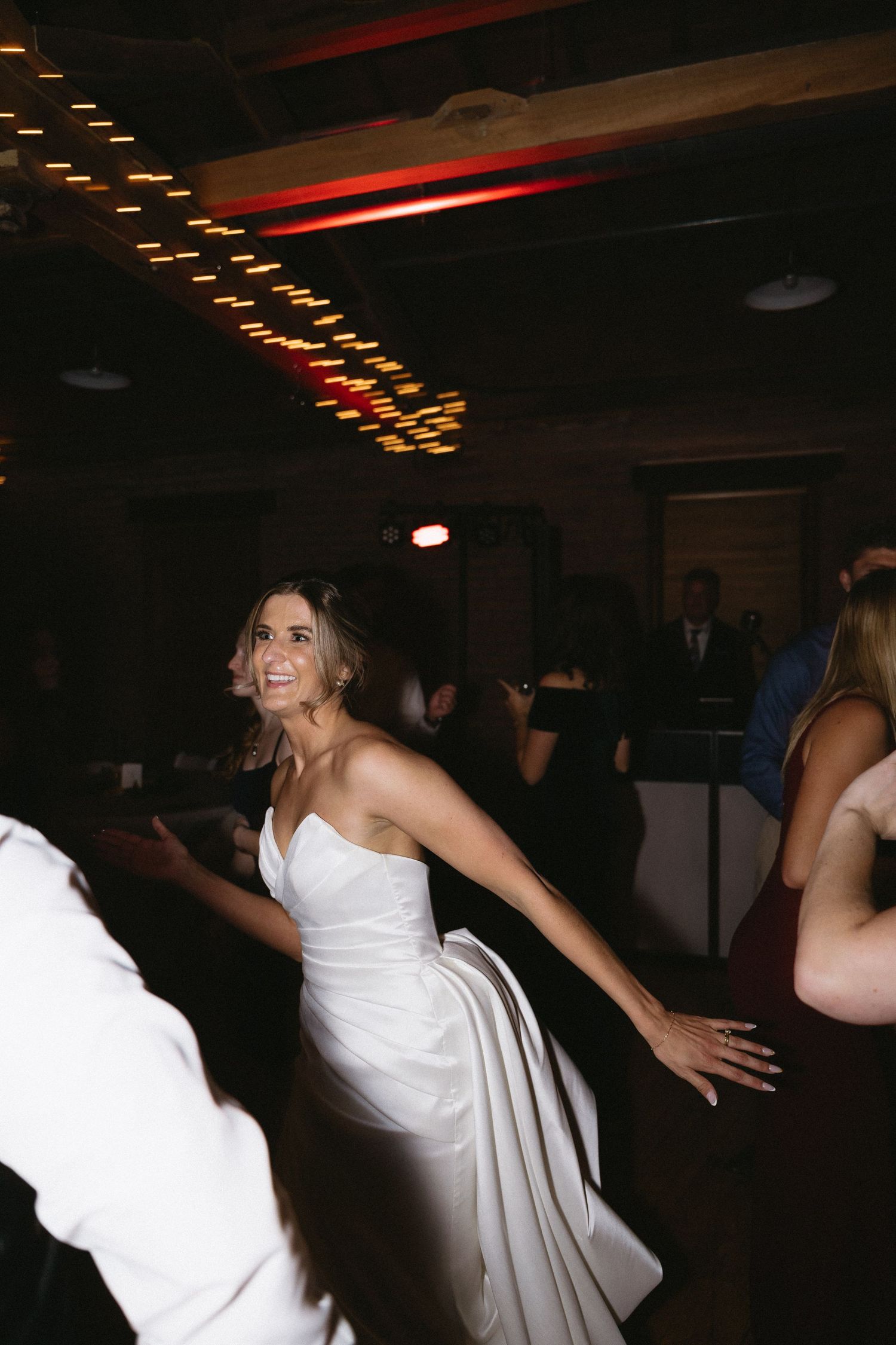 Bride dances exuberantly with family and friends during her wedding after party at a historic tavern in downtown Boston, Massachusetts