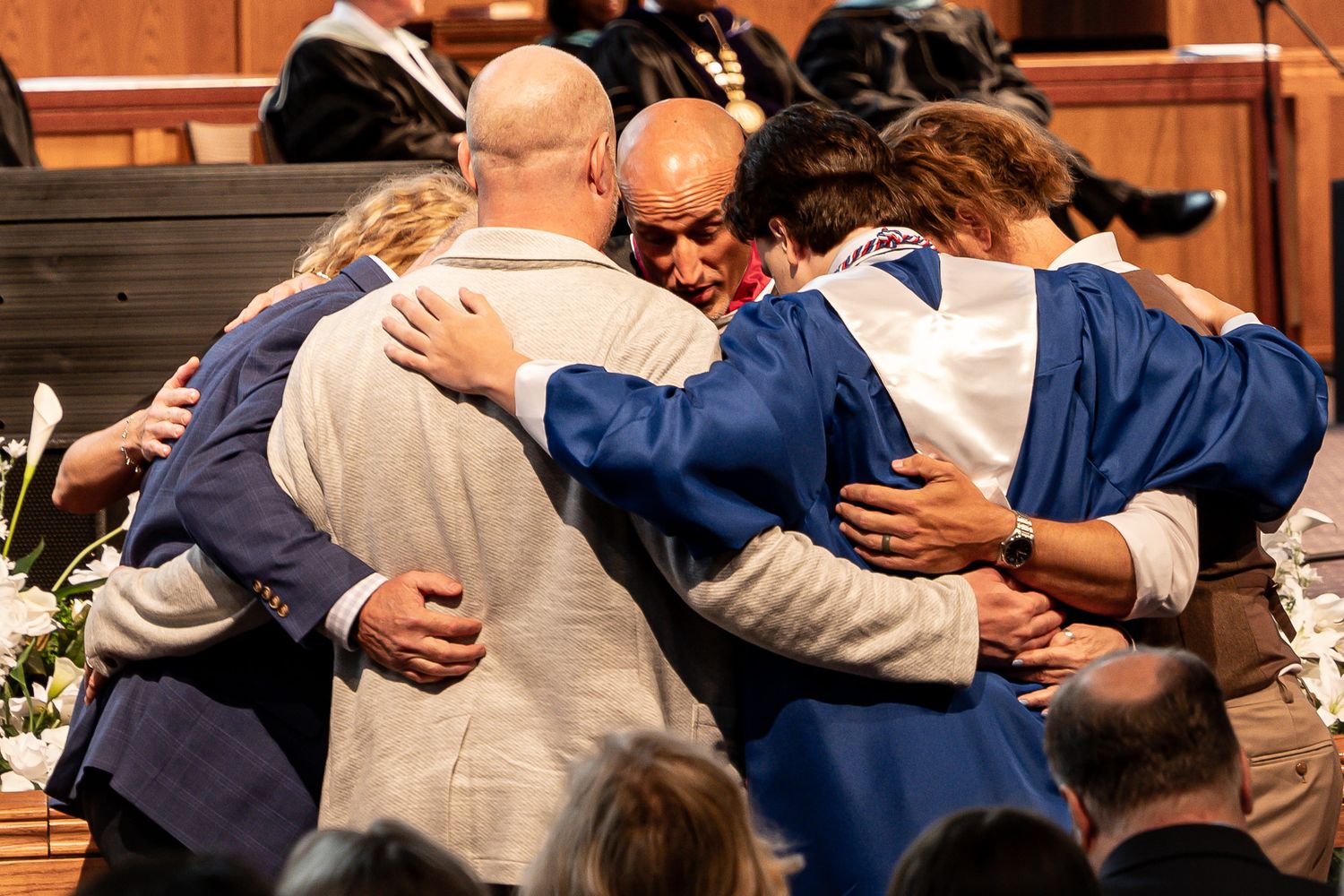 Family portrait of a young man being embraced by his family and pastor at his Christian high school graduation party in Georgia
