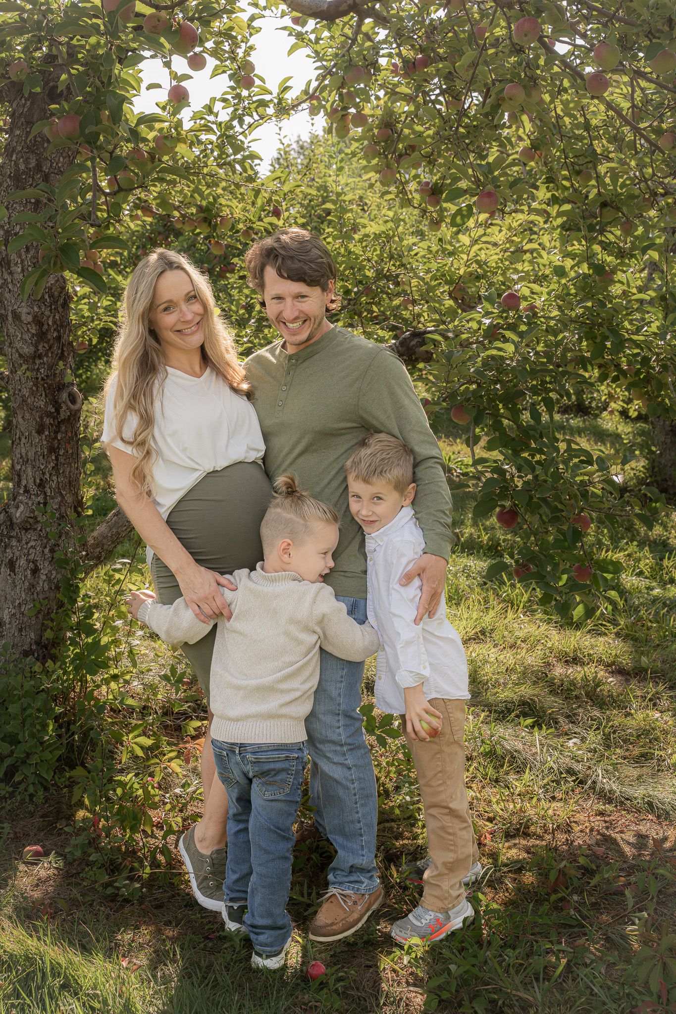 Family portrait of a pregnant mom, a dad, and their two sons smiling on a Fall day at Applecrest Orchards in Hampton Falls, New Hampshire