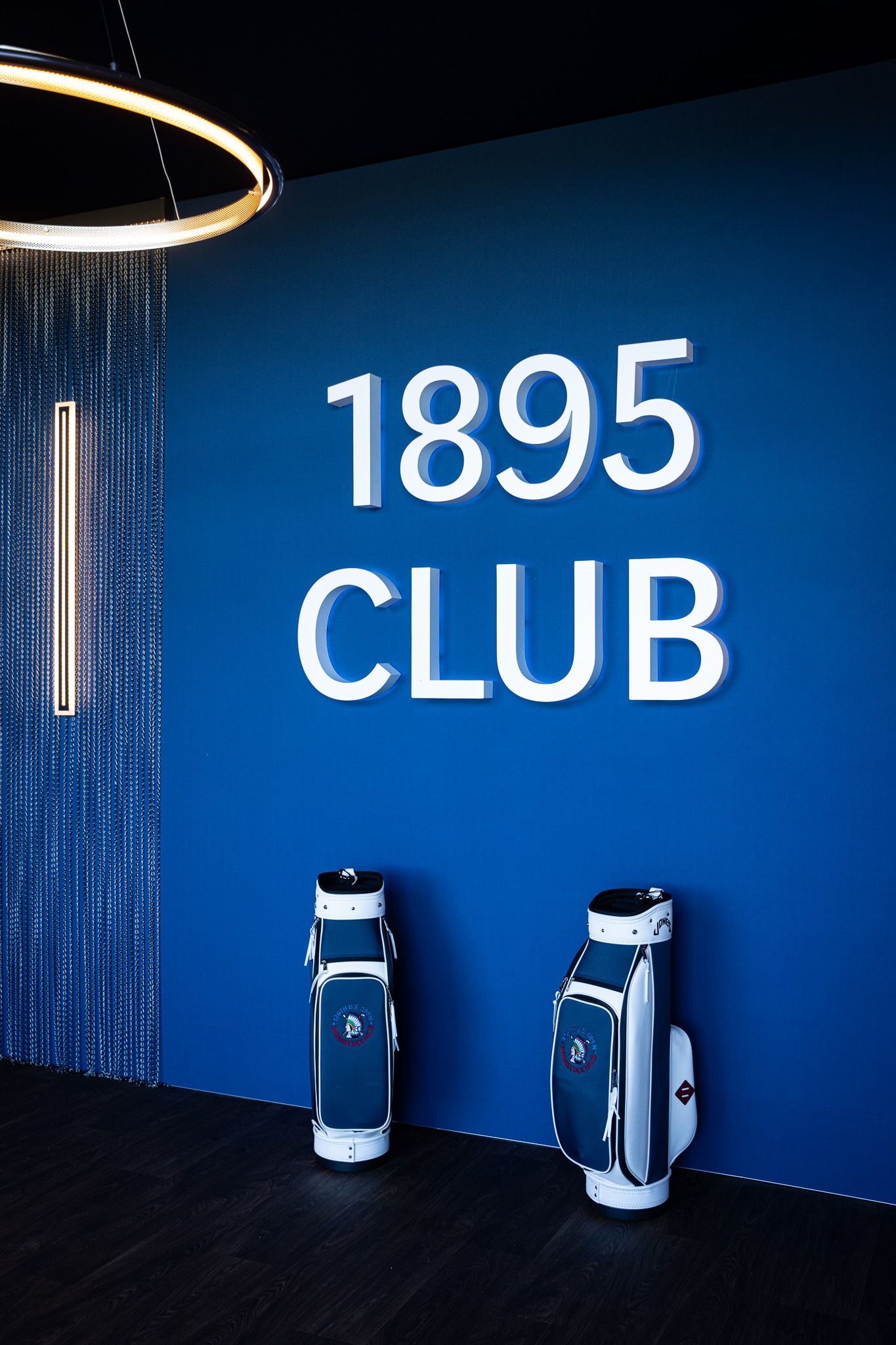 Event photography of two golf bags against a bold blue wall inside the 1895 Club at the U.S. Open Golf Championship in the Hamptons, NY