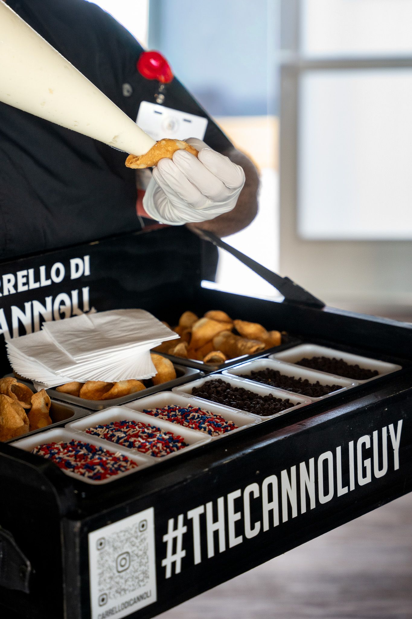 Event photography of a man wearing a hawker tray making cannolis in the 1895 club at the U.S. Open Golf Championship in the Hamptons, NY