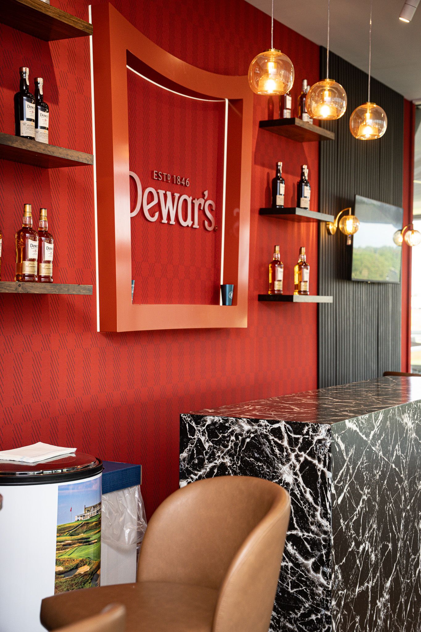 Corporate event photography of a company suite at the U.S. Open Golf Championship in the Hamptons, NY featuring a  moody red Scotch bar