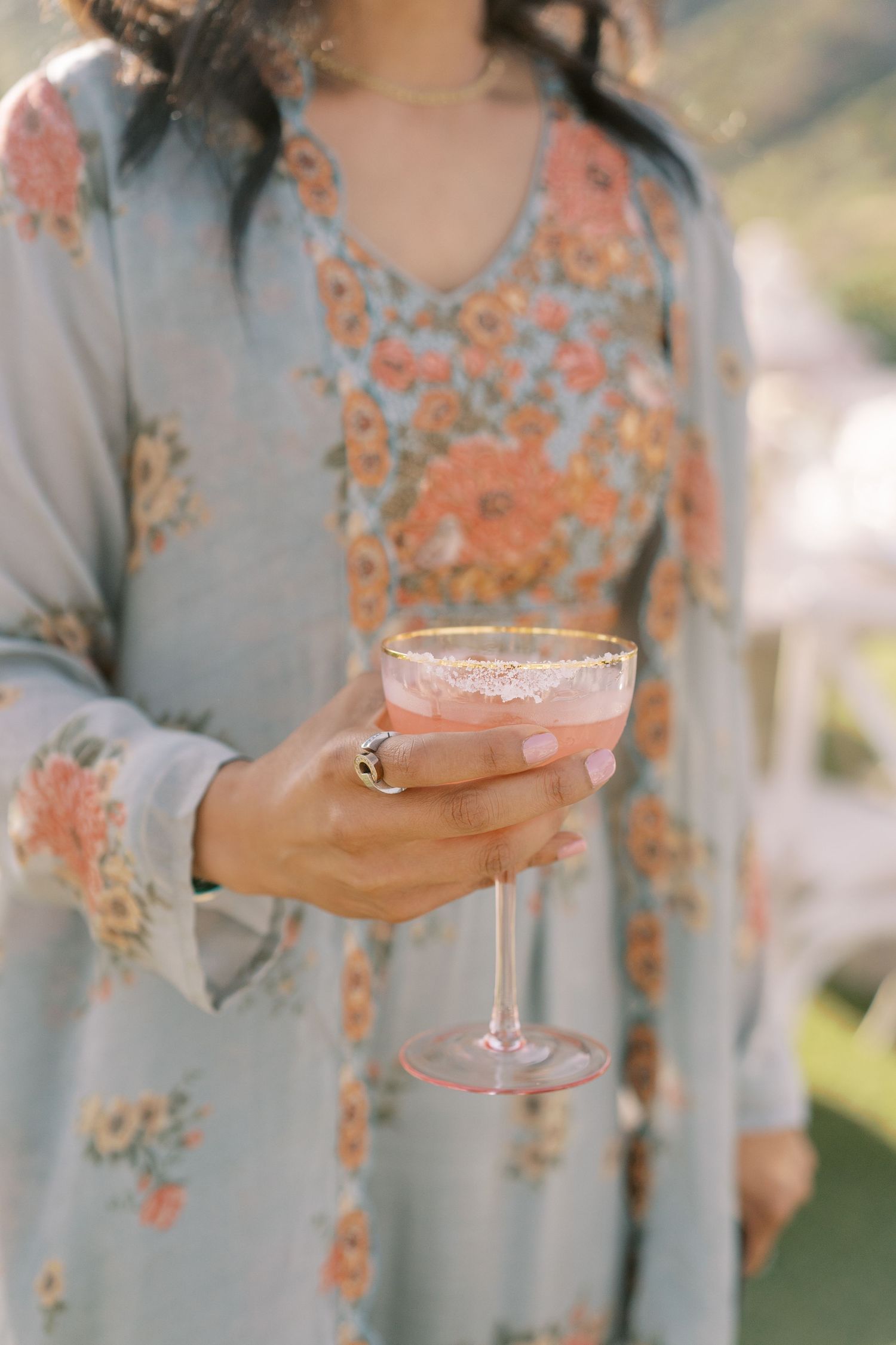 Woman in elegant embellished beaded dress holds a signature drink during cocktail hour at an Indian wedding in New England