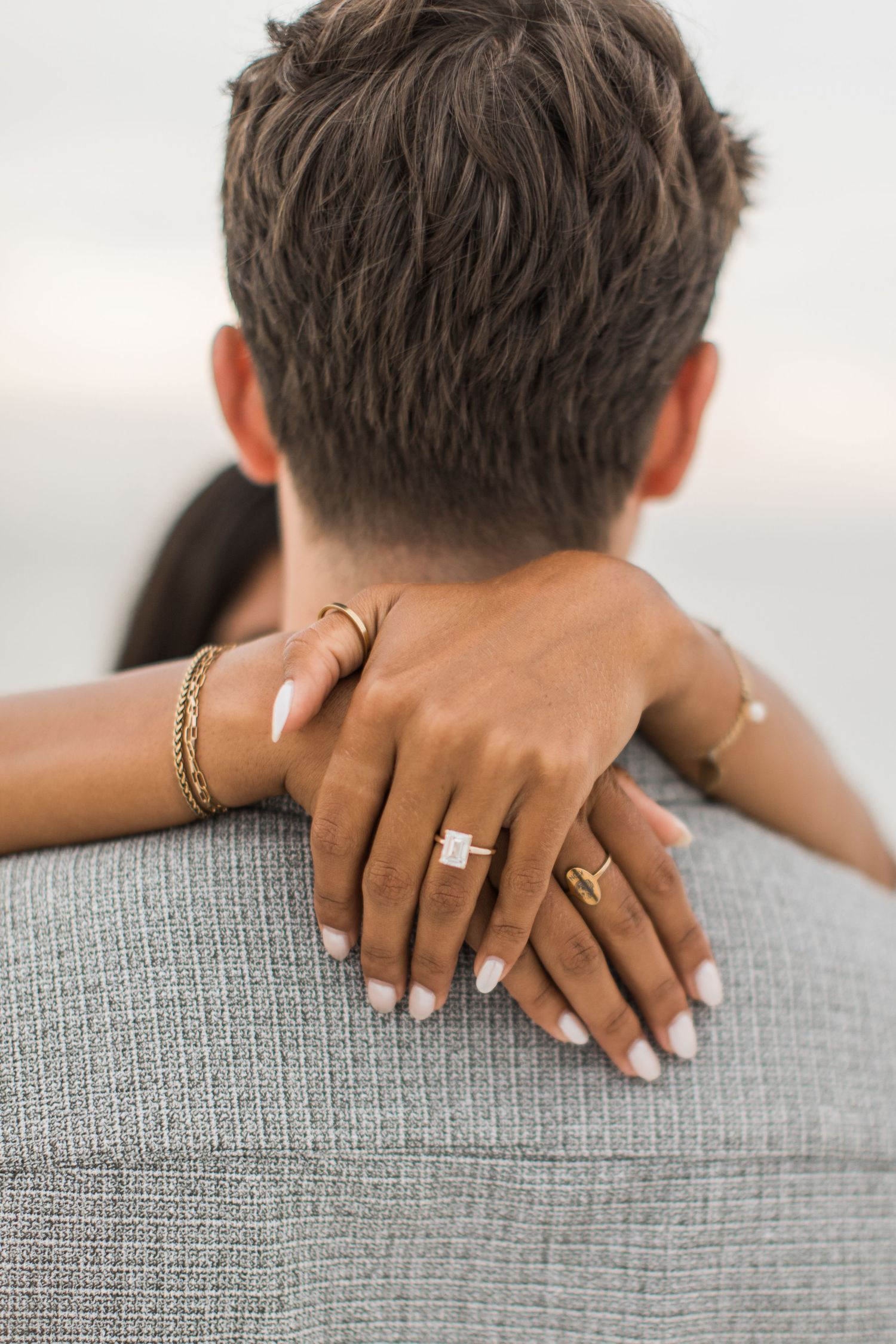 Engagement photo of a woman's hands gently wrapped around her fiancé's shoulders showing off her new diamond ring in Boston, Massachusetts